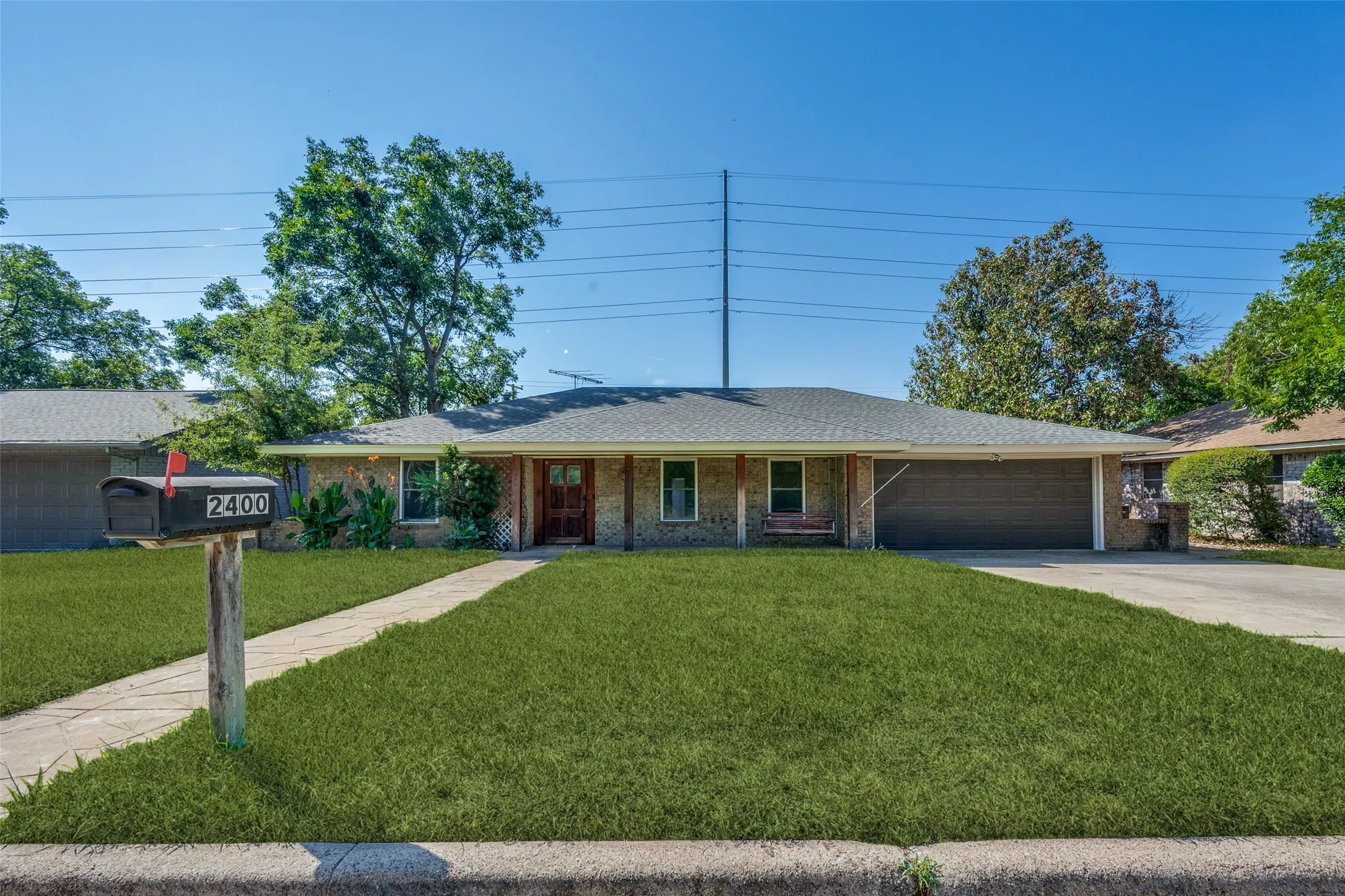 Brick and stone facade, covered entry, attached two-car garage, concrete driveway, and front walkway
