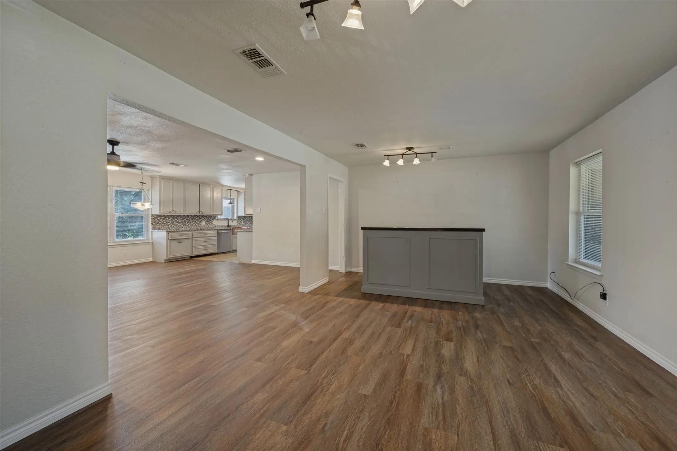 Spacious interior with wood-finish flooring, a built-in bar, and track lighting