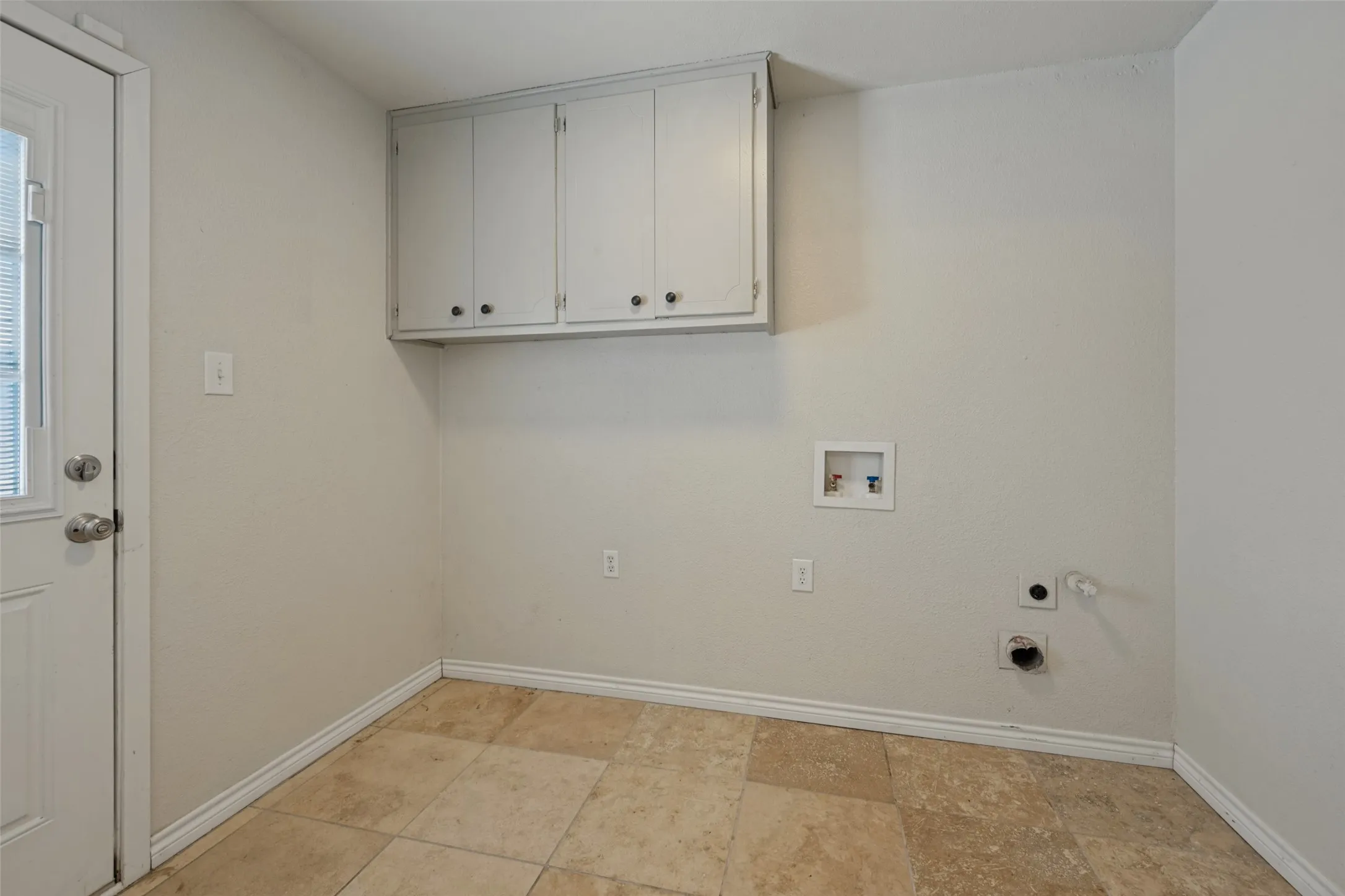 Overhead cabinetry, tile flooring, and a rear exterior door