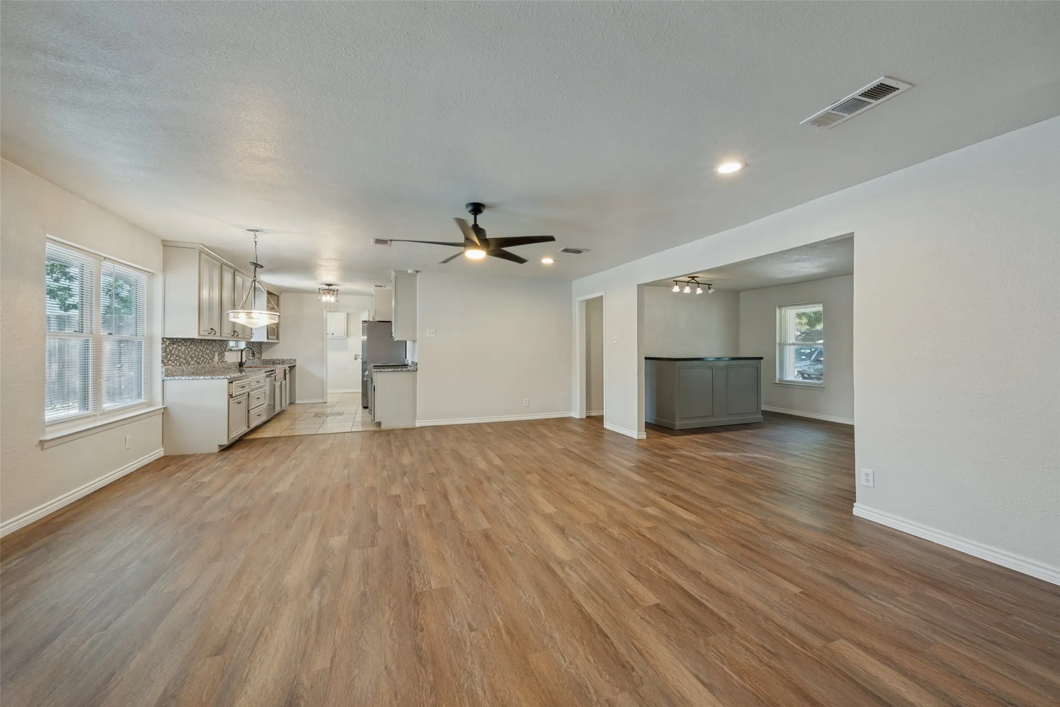 Open concept layout with wood-finish flooring, recessed lighting, and a contemporary ceiling fan