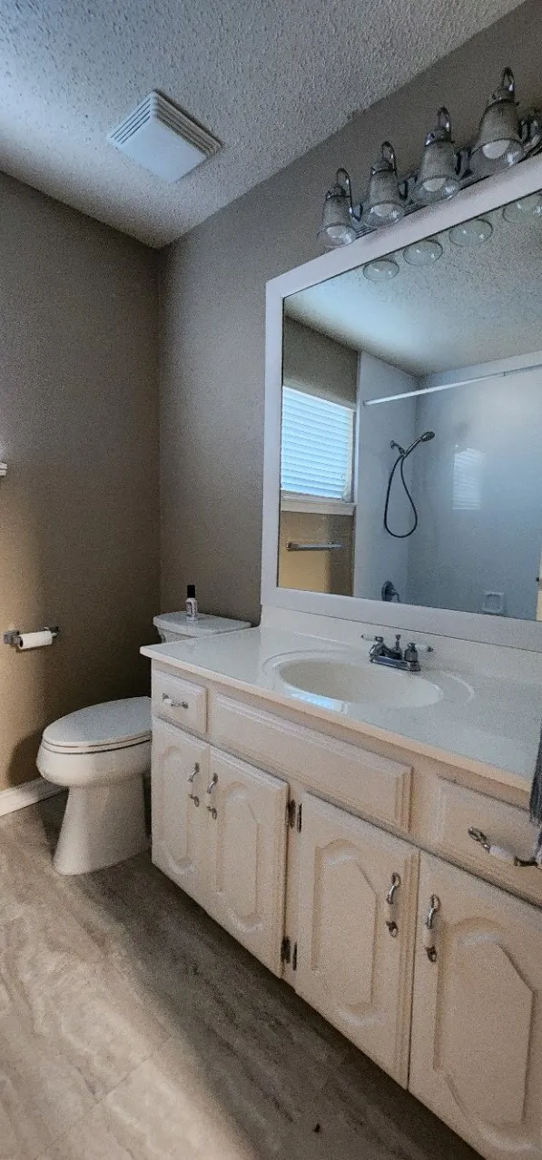 White vanity with a laminate countertop, integrated sink, and chrome faucet