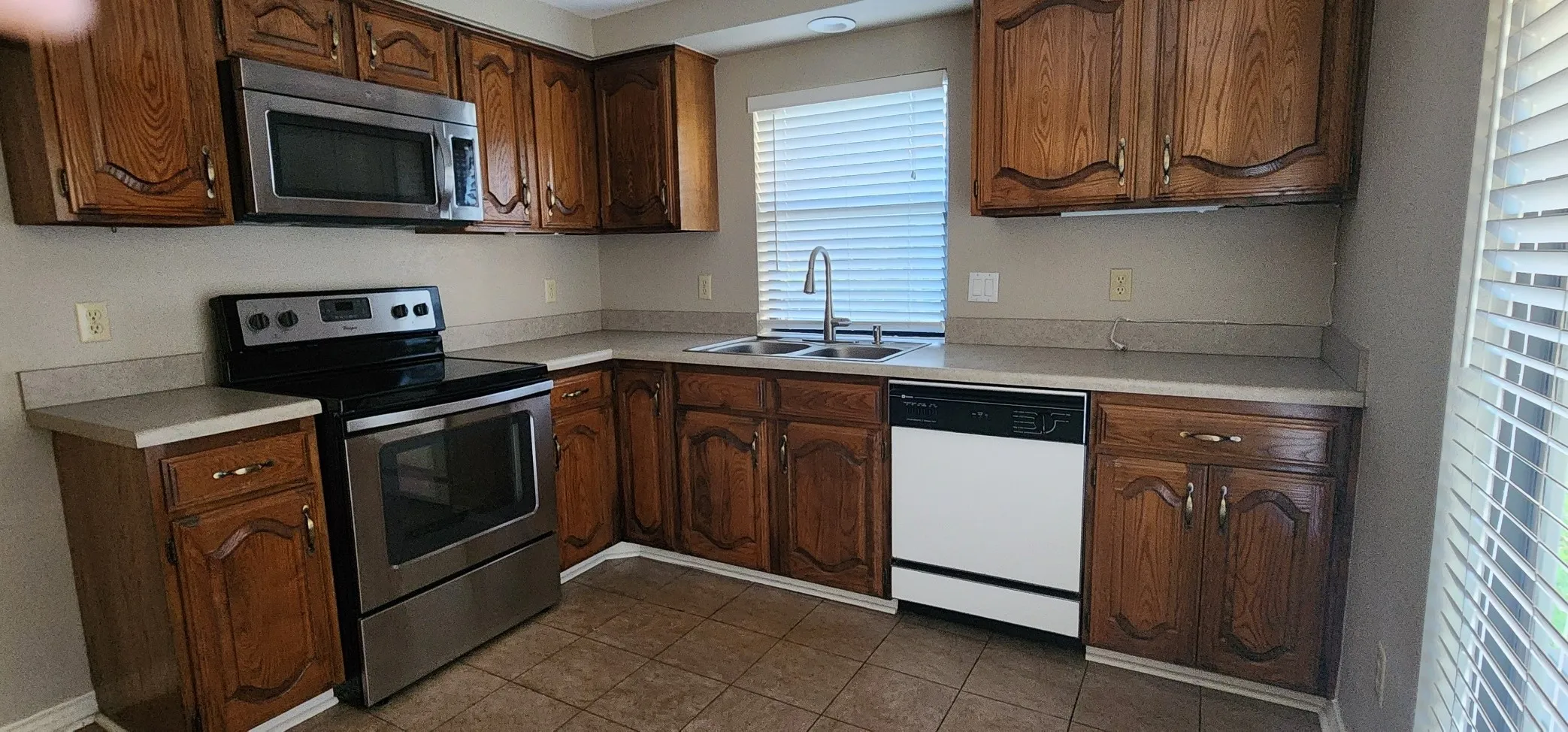 Kitchen featuring wood cabinetry, stainless steel microwave, stainless steel range, and a dual basin sink