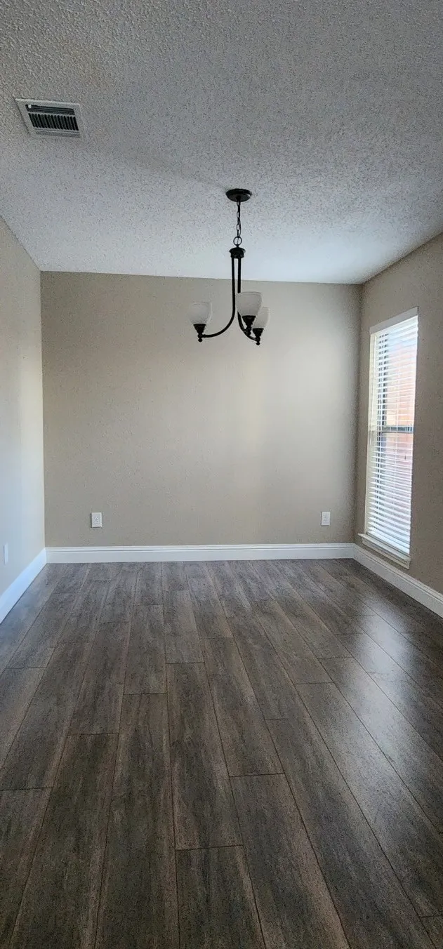 Wood-finish flooring, neutral wall tones, white trim, and a three-light chandelier