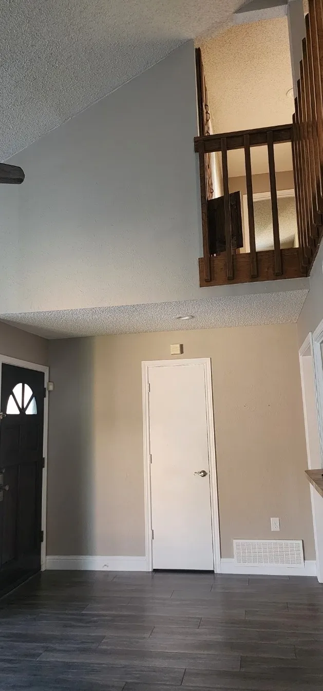 Vaulted ceiling with a wood-finish ceiling fan, wood-finish flooring, and an interior balcony with wood railing