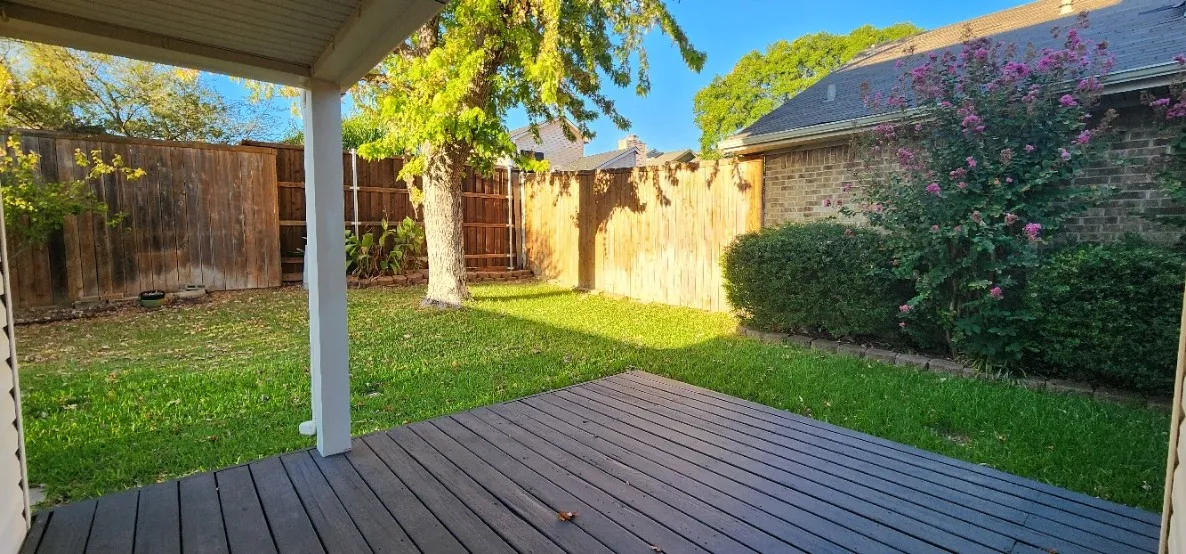 Covered patio with a composite deck, grassy yard, and wood privacy fencing