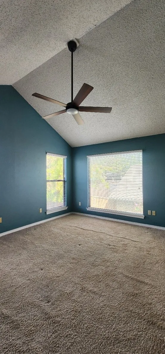 Vaulted ceiling with a ceiling fan, two windows with blinds, and wall-to-wall carpeting
