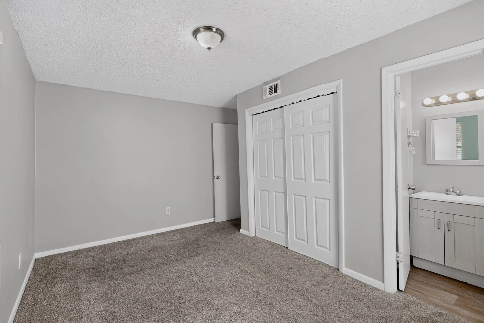 Plush gray carpeting, light gray wall paint, white bi-fold closet doors, and recessed lighting