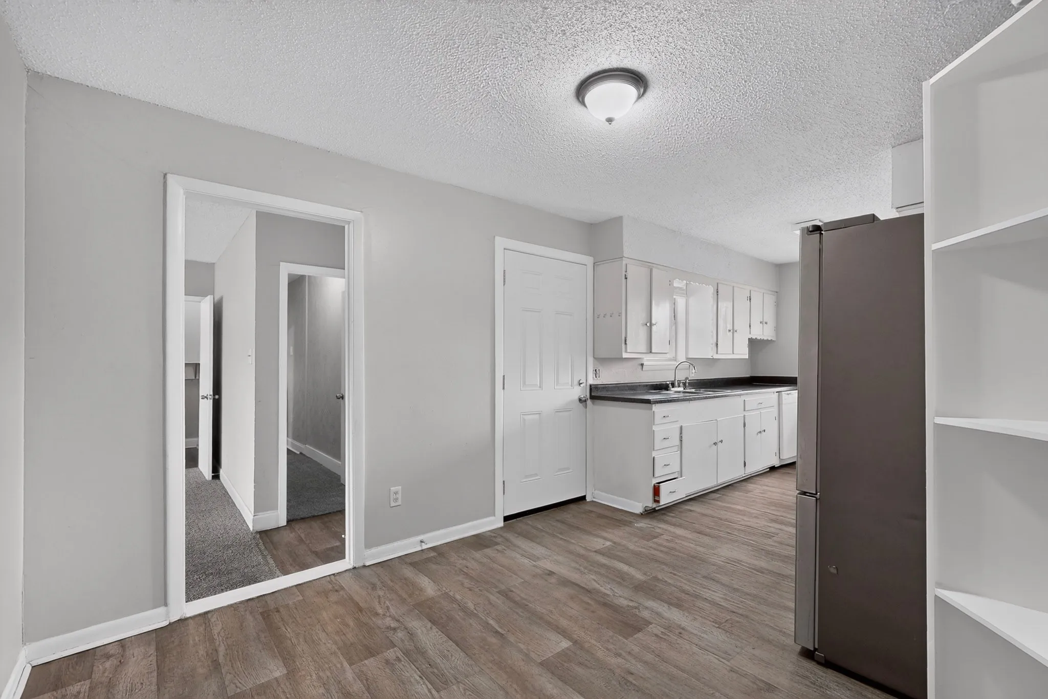 Wood-finish flooring, white cabinetry, dark countertops, built-in shelving, and neutral wall paint