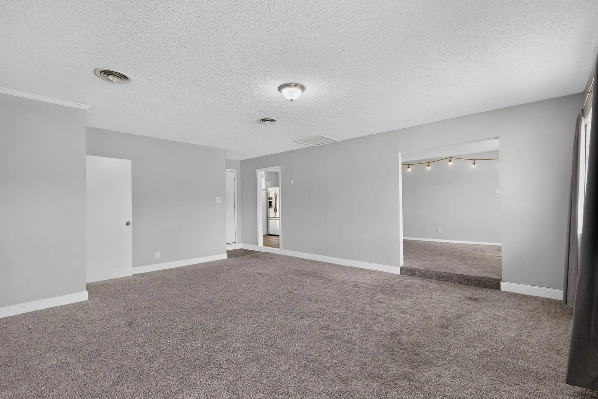 Light gray painted walls with white trim, gray carpet, and semi-flush mount ceiling lighting