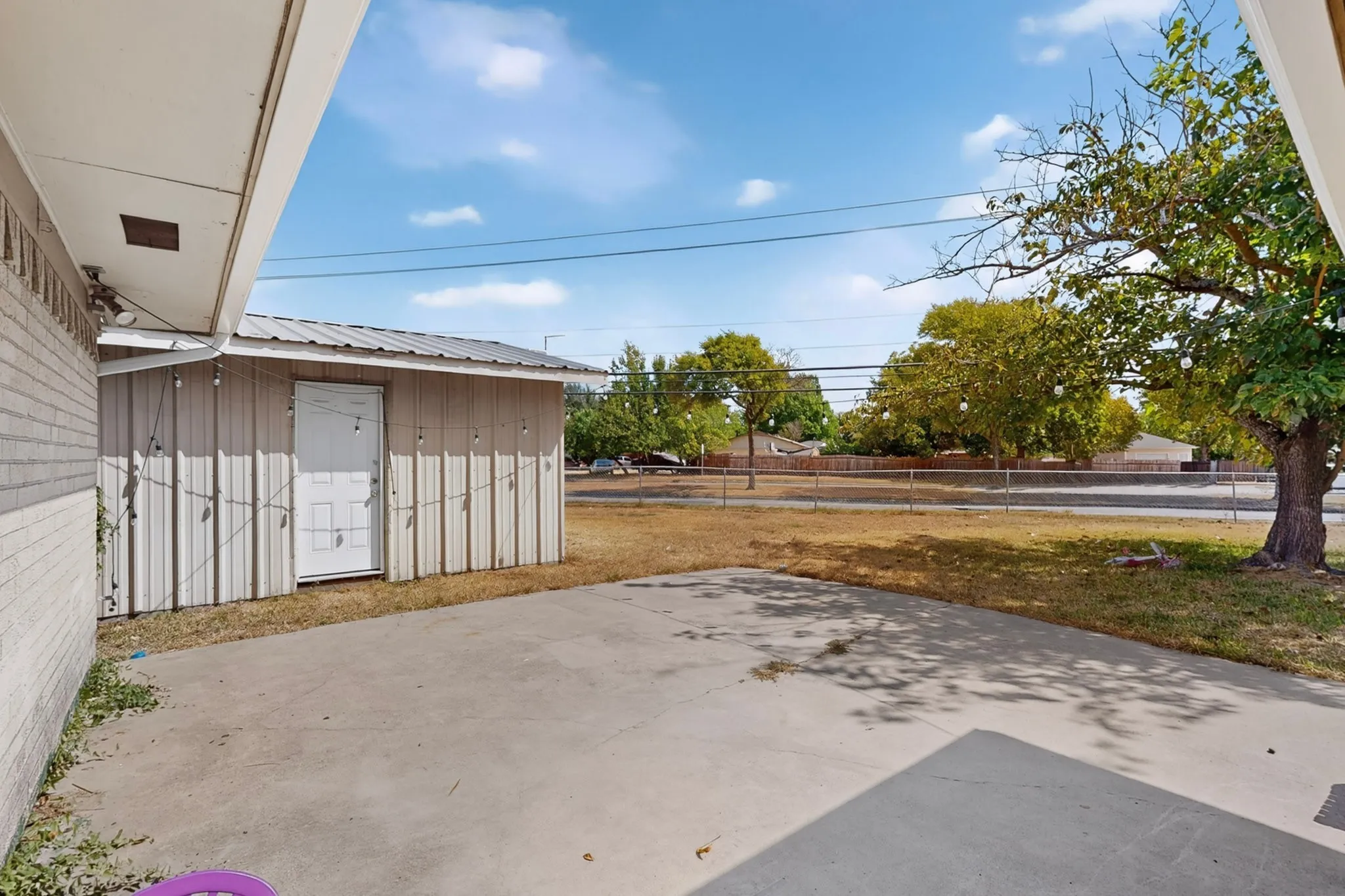 Concrete patio with a detached storage shed featuring a metal roof and a side entry door