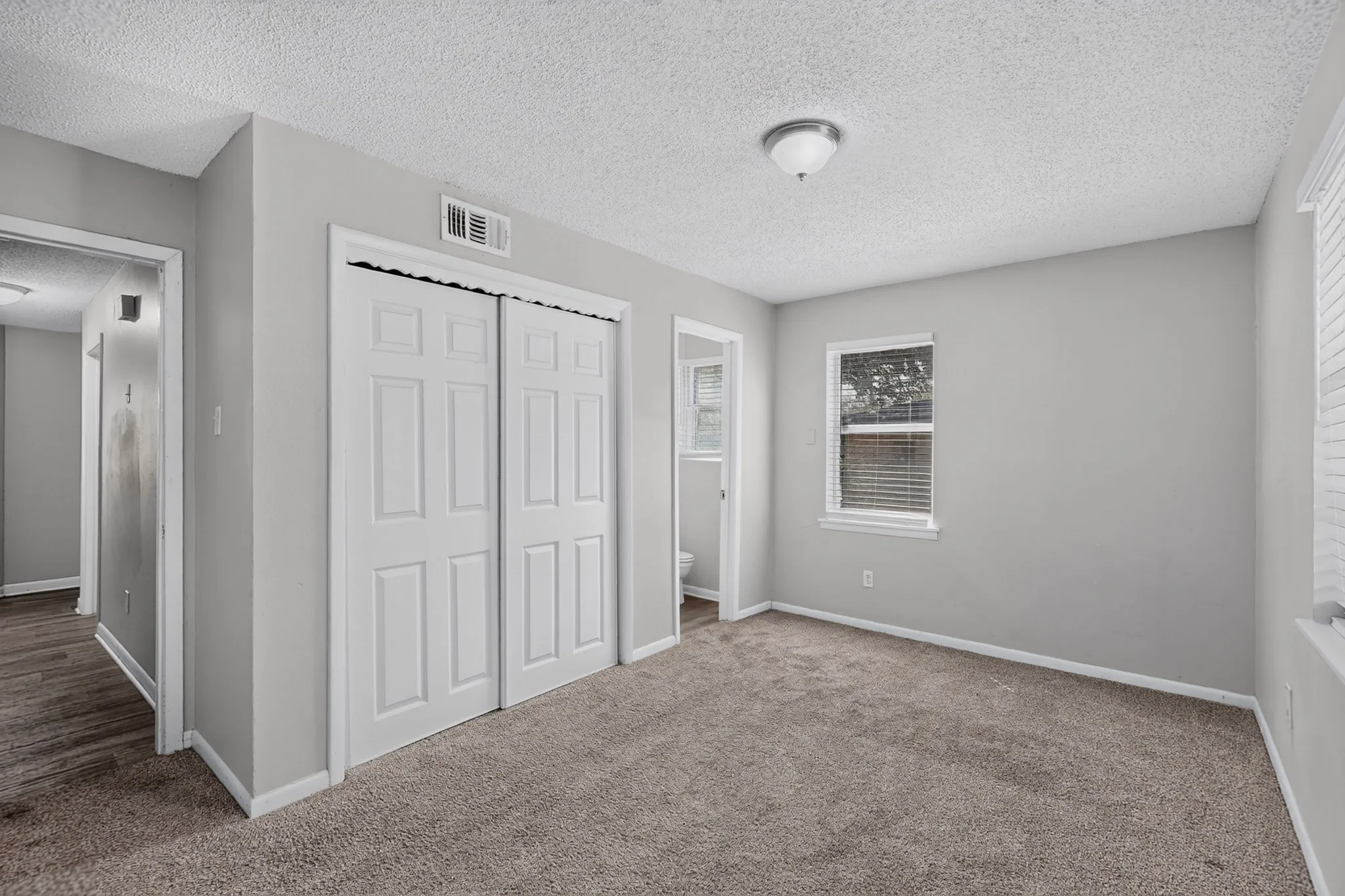 Carpeted room with a window, white paneled bifold closet doors, and recessed lighting