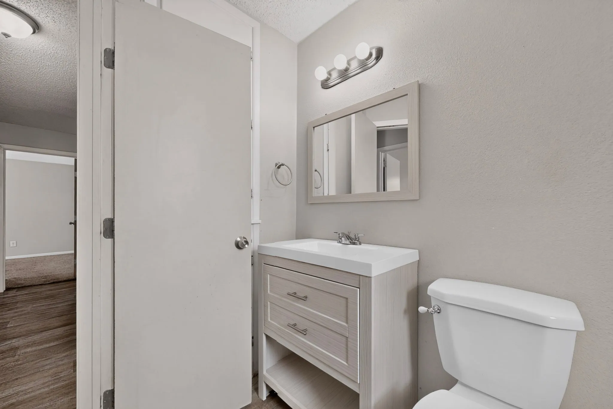 Bathroom featuring a light-toned vanity with an integrated sink, wall-mounted mirror, and a toilet