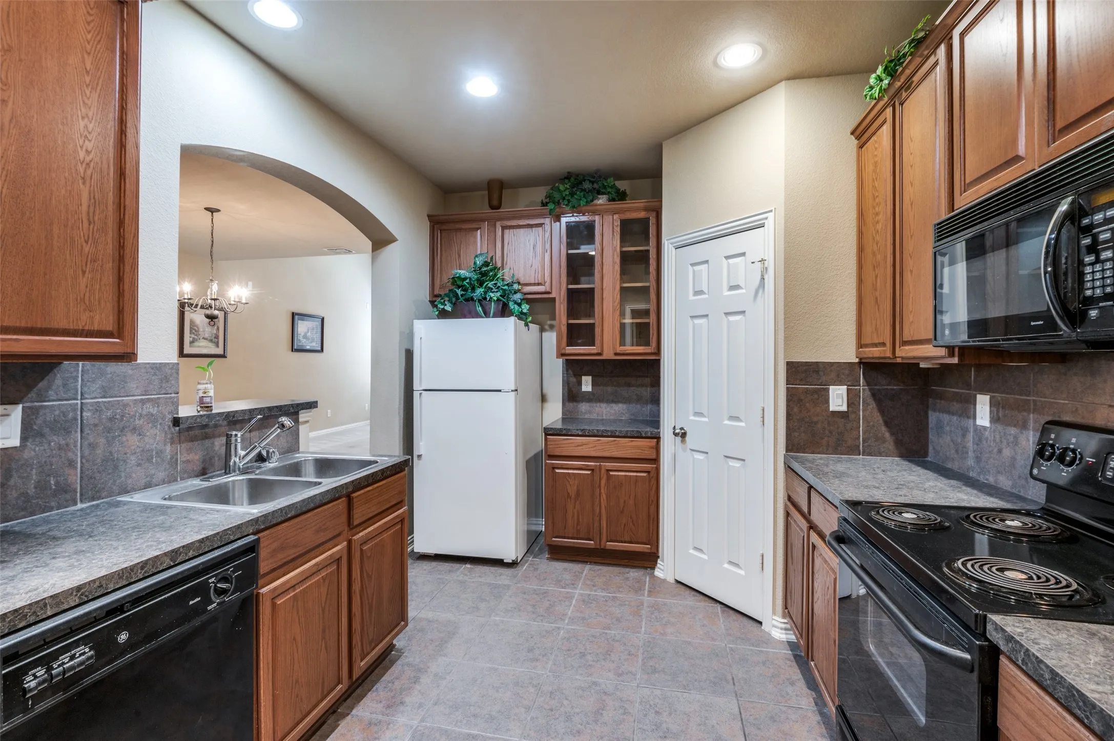 Kitchen featuring wood cabinetry, stone-look countertops, and tile flooring