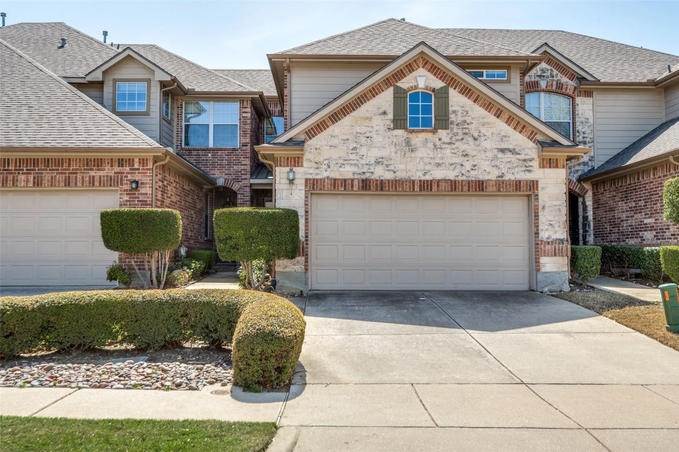 Two-story exterior with brick and stone accents, featuring a two-car garage and manicured landscaping