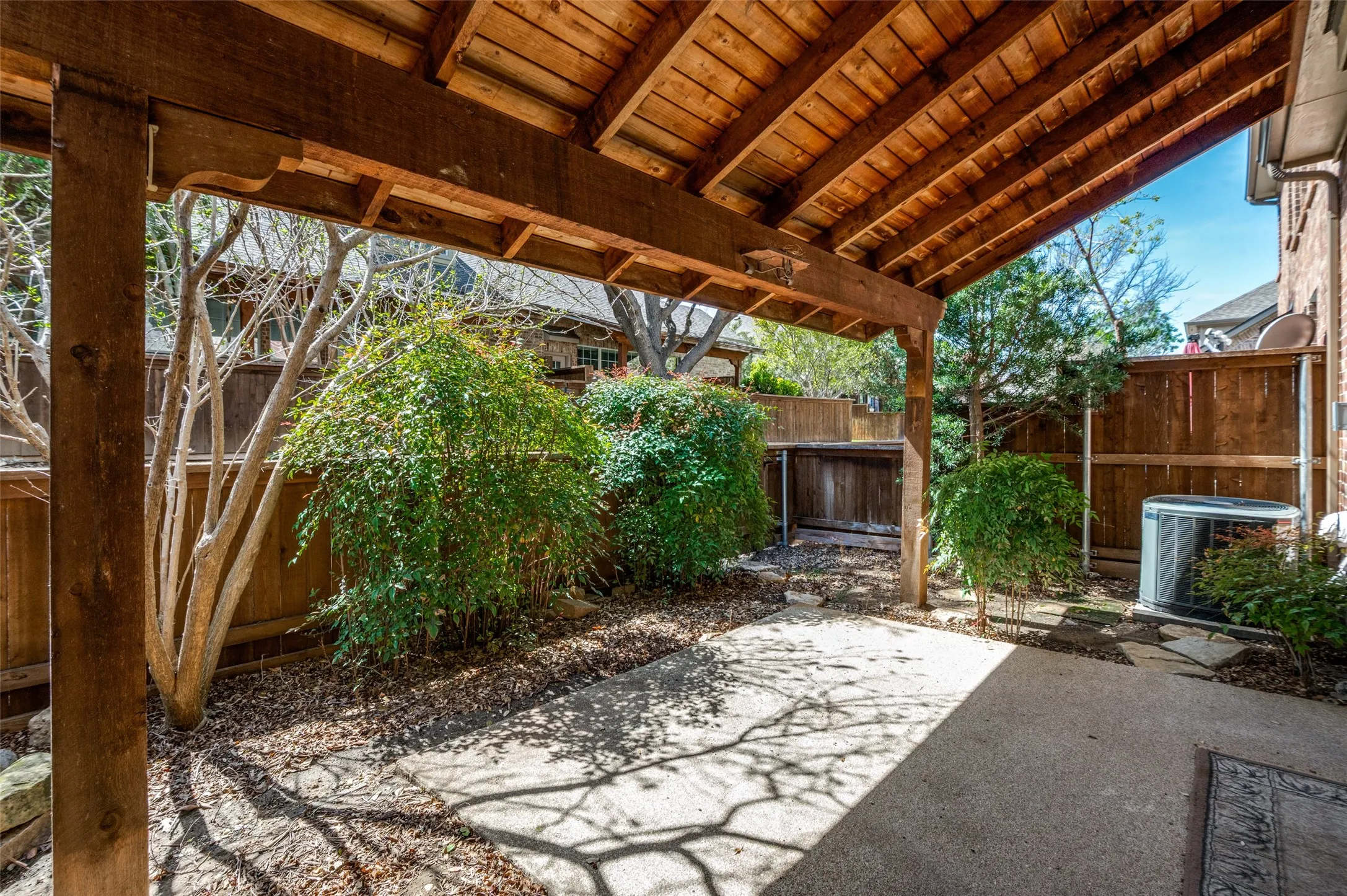 Covered patio with a wood-finish ceiling, exposed beams, and concrete flooring