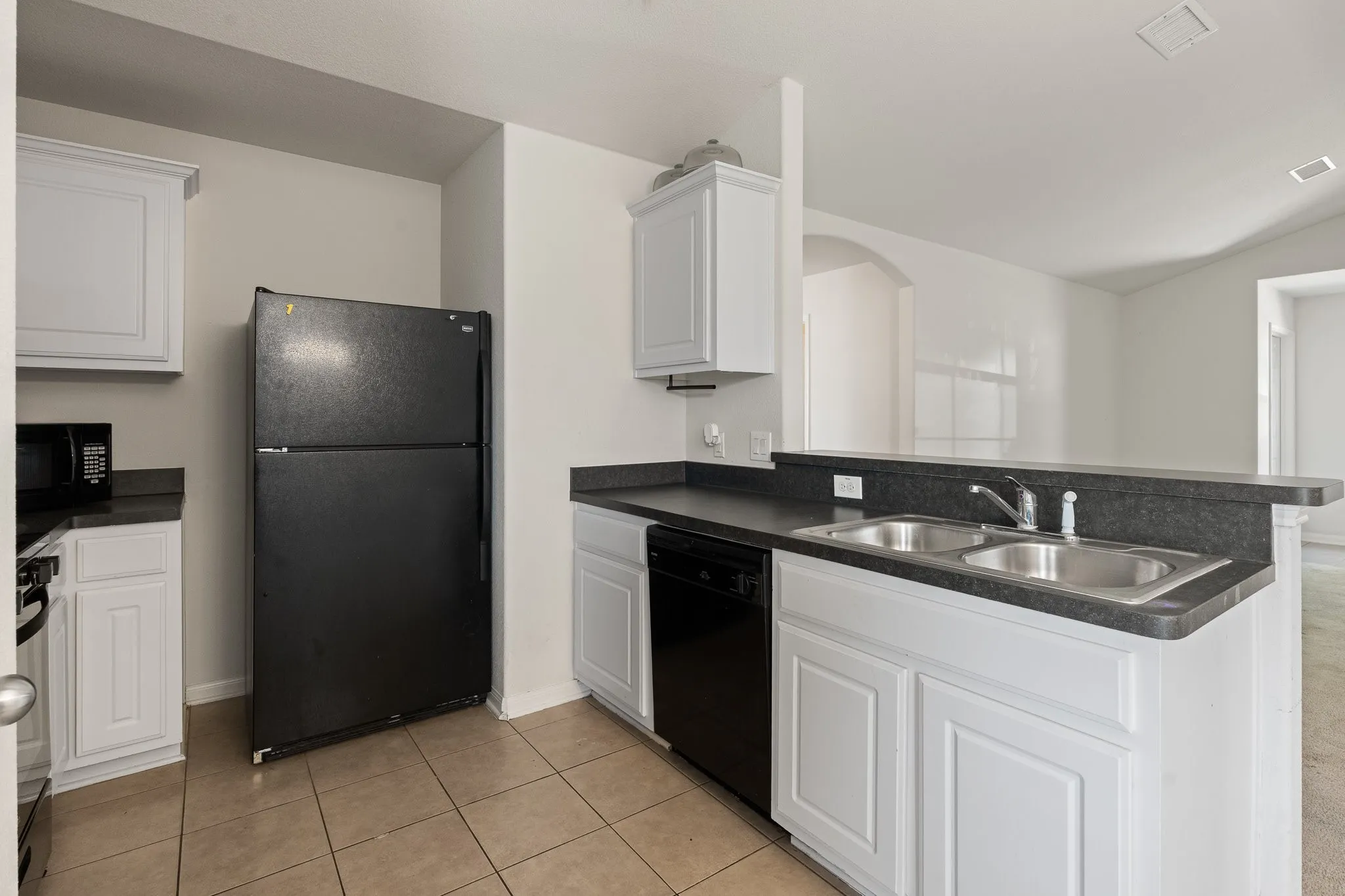Kitchen featuring white cabinetry. Refrigerator stays with property