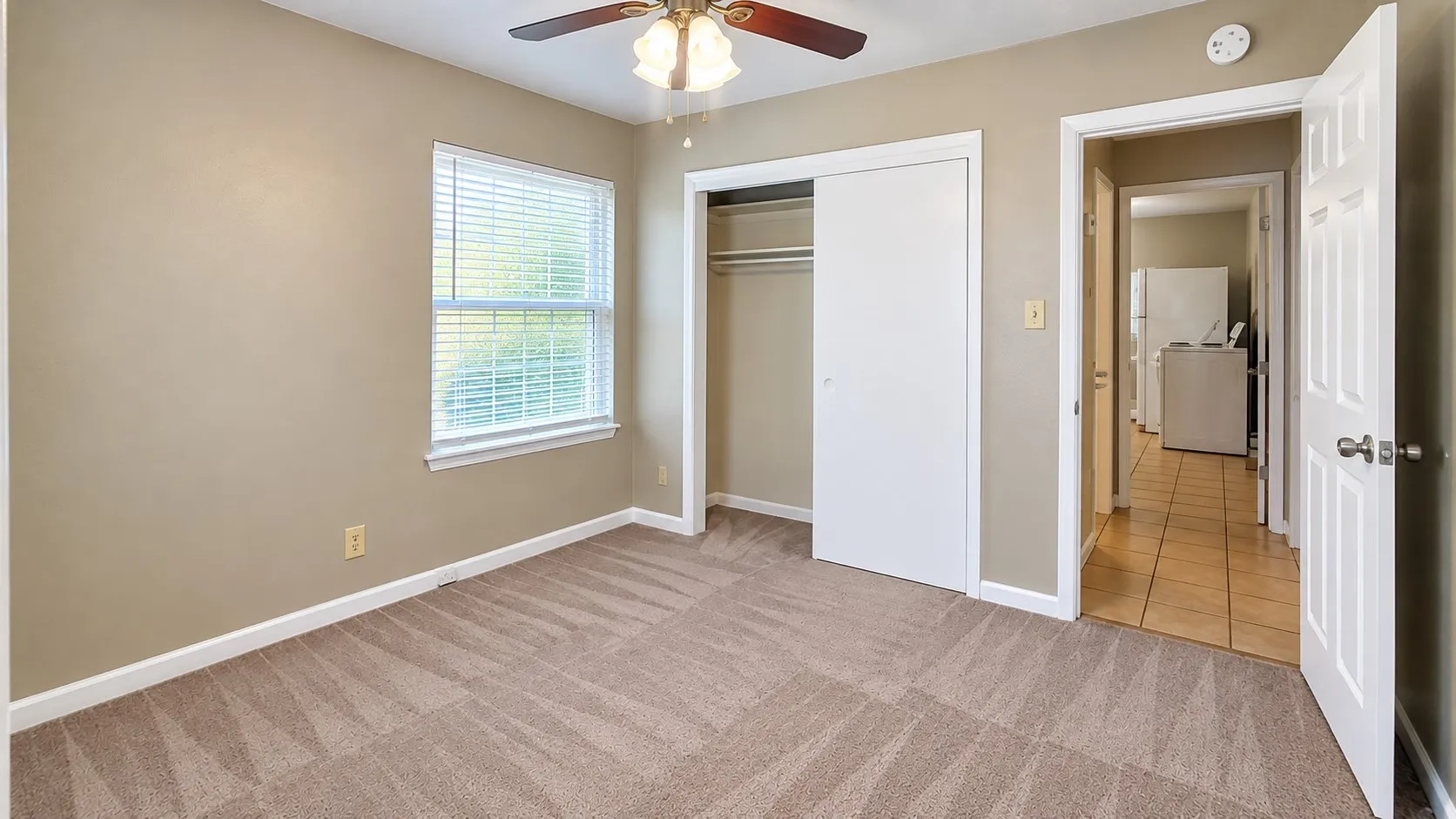 Carpeted room with a window, white trim, and a ceiling fan