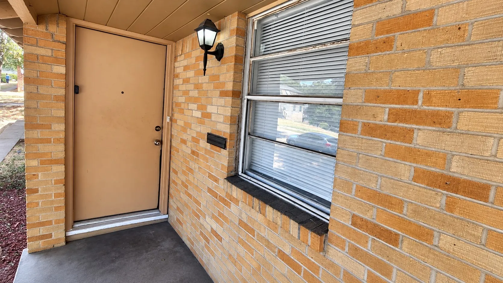 Brick exterior with an entryway sconce and a front window