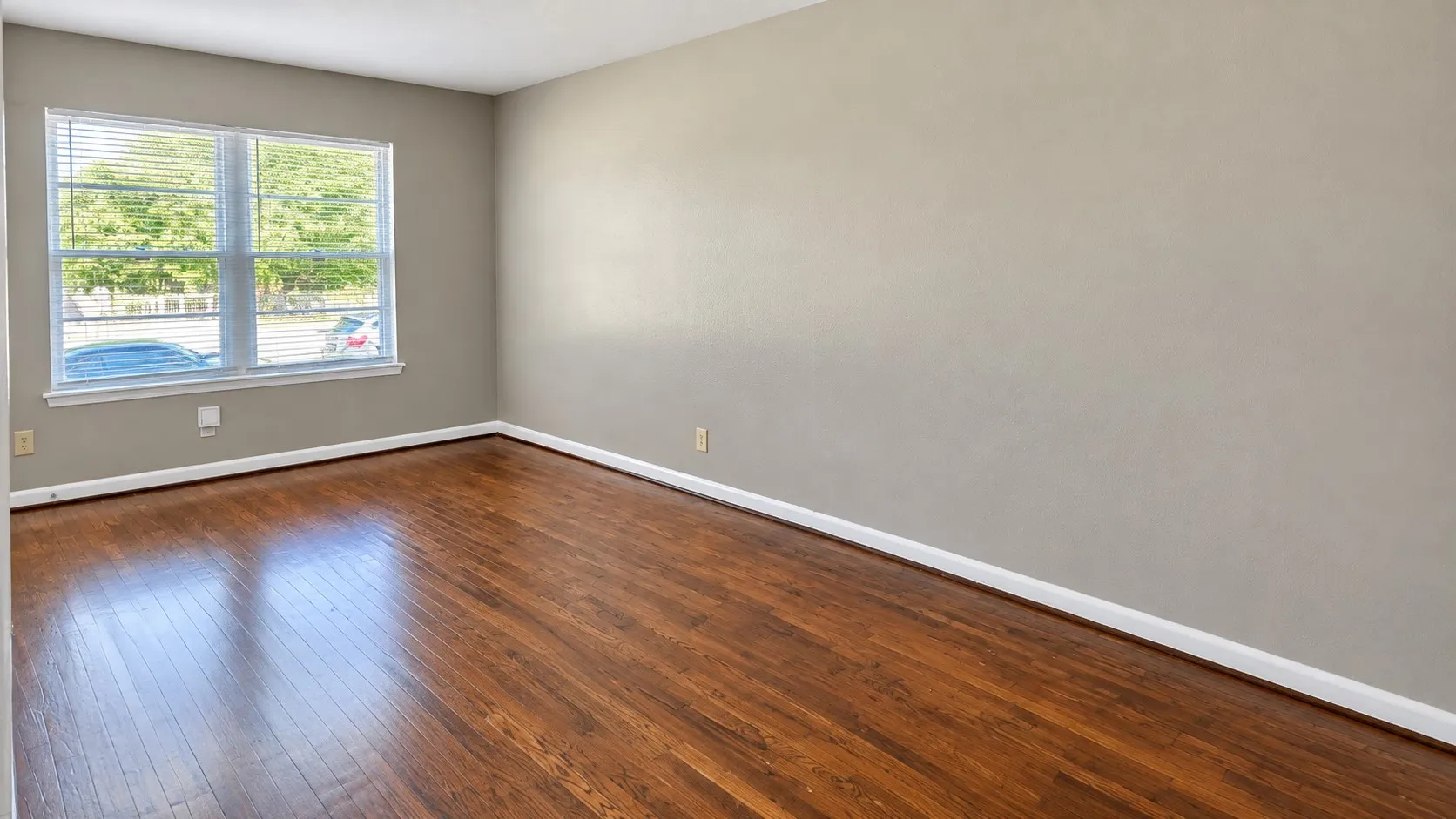 Wood-finish flooring, neutral wall tones, and a window with horizontal blinds