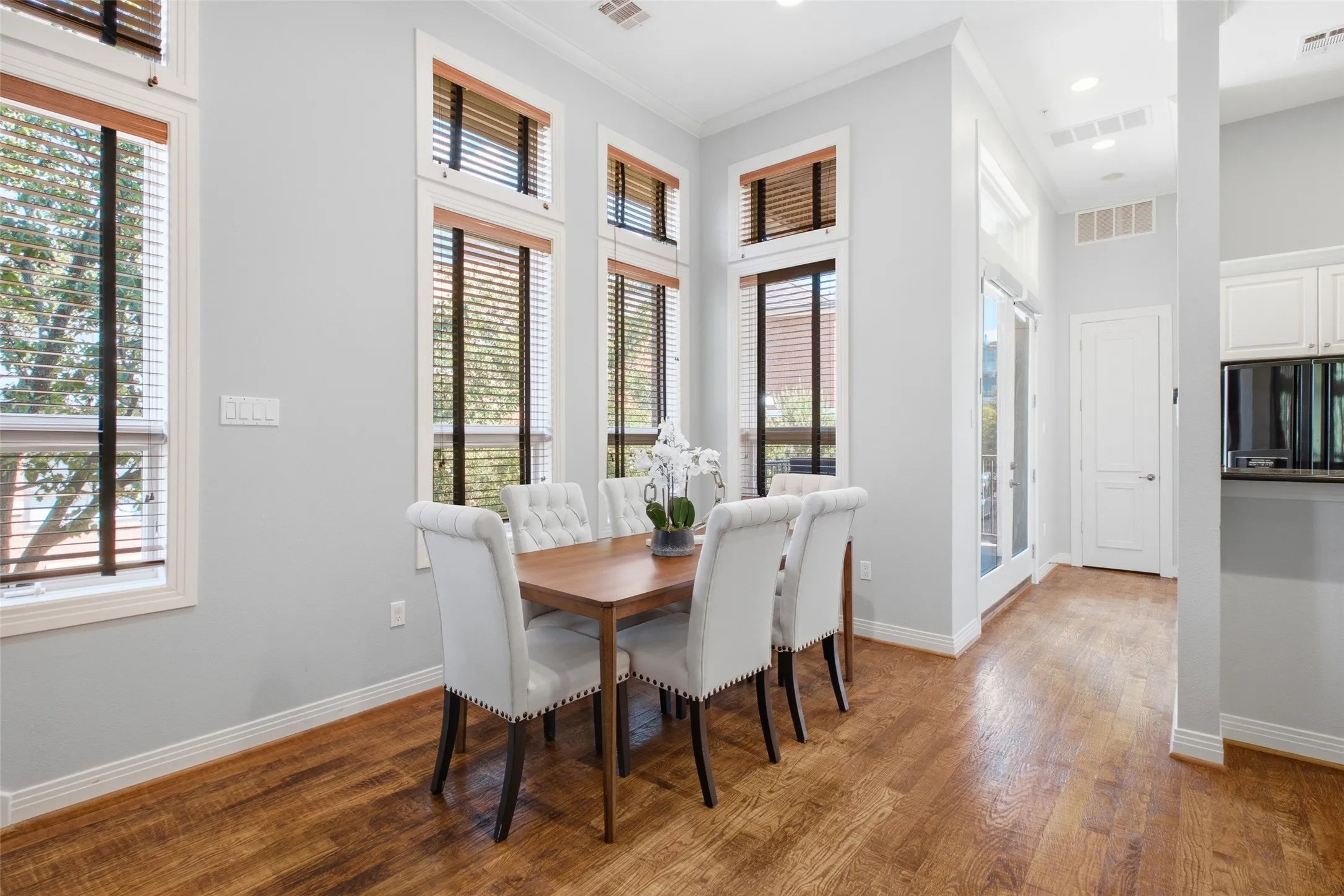 Dining sits right off the kitchen under stacked transom windows and rich hardwood floors