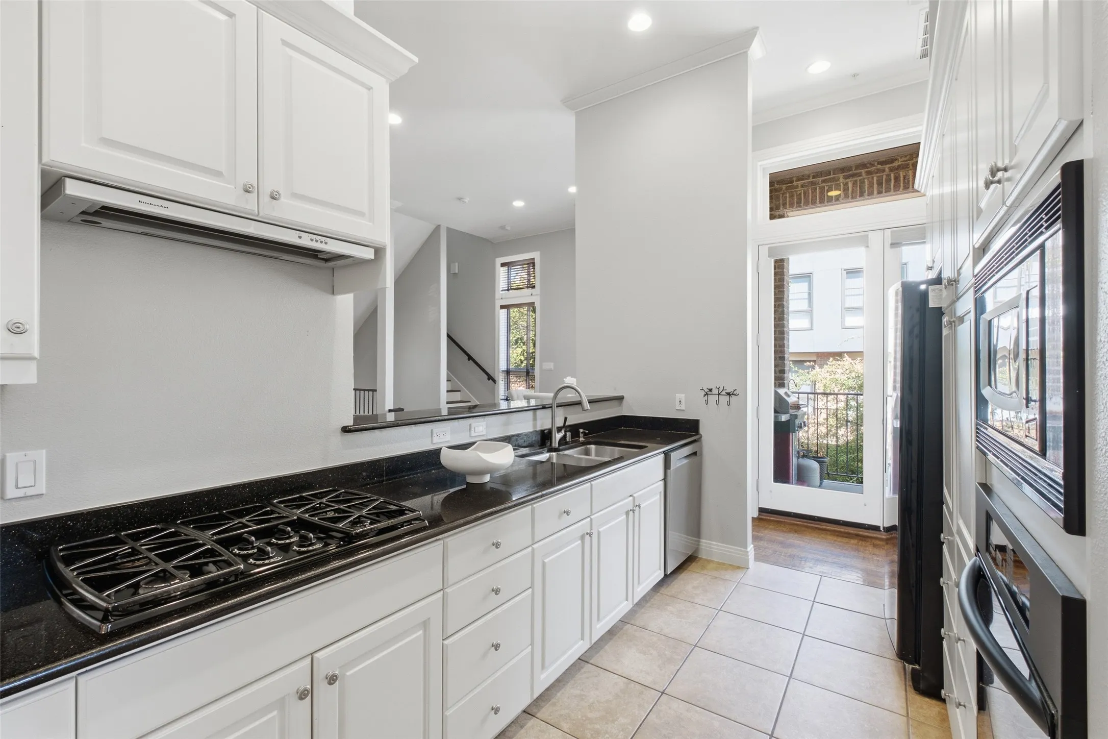 Gas cooktop under a range hood, built-in oven and microwave, and a door out to the balcony