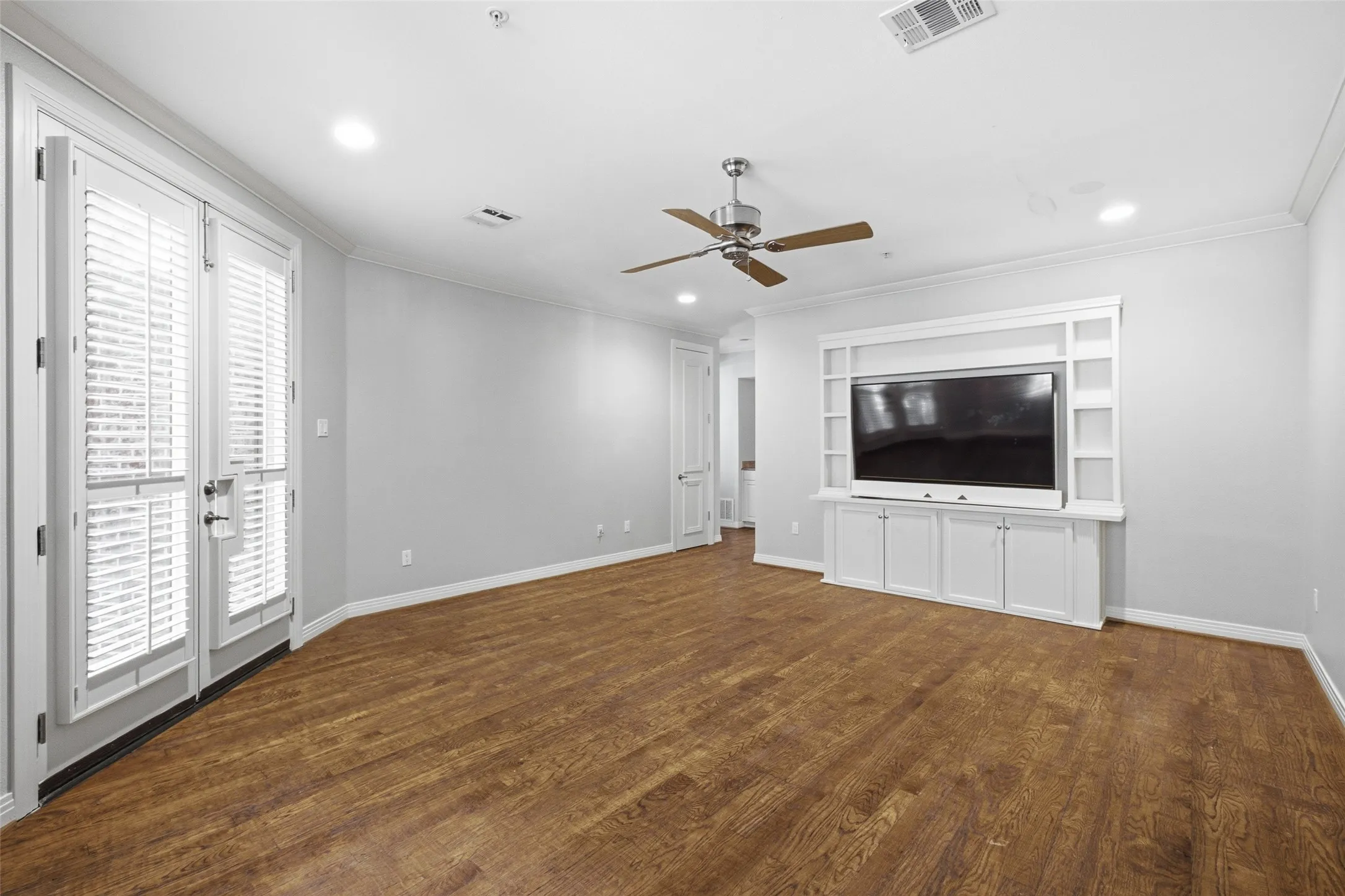 Built-in media cabinetry and shutter-clad French doors finish the entry-level flex room