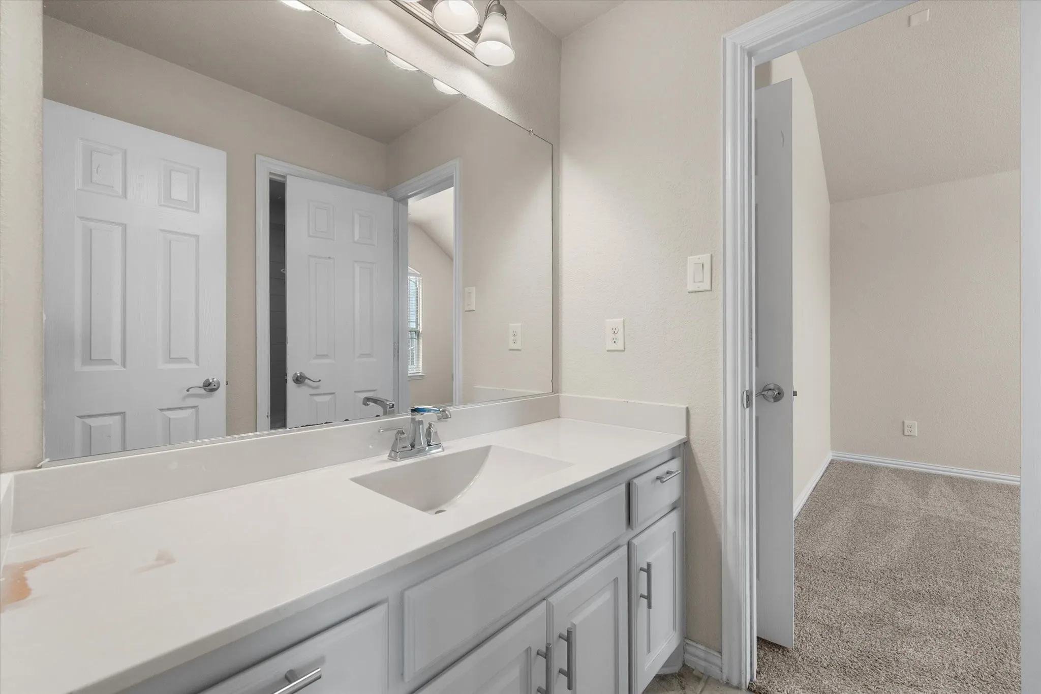 White vanity with chrome hardware, an integrated sink, and a large wall-mounted mirror