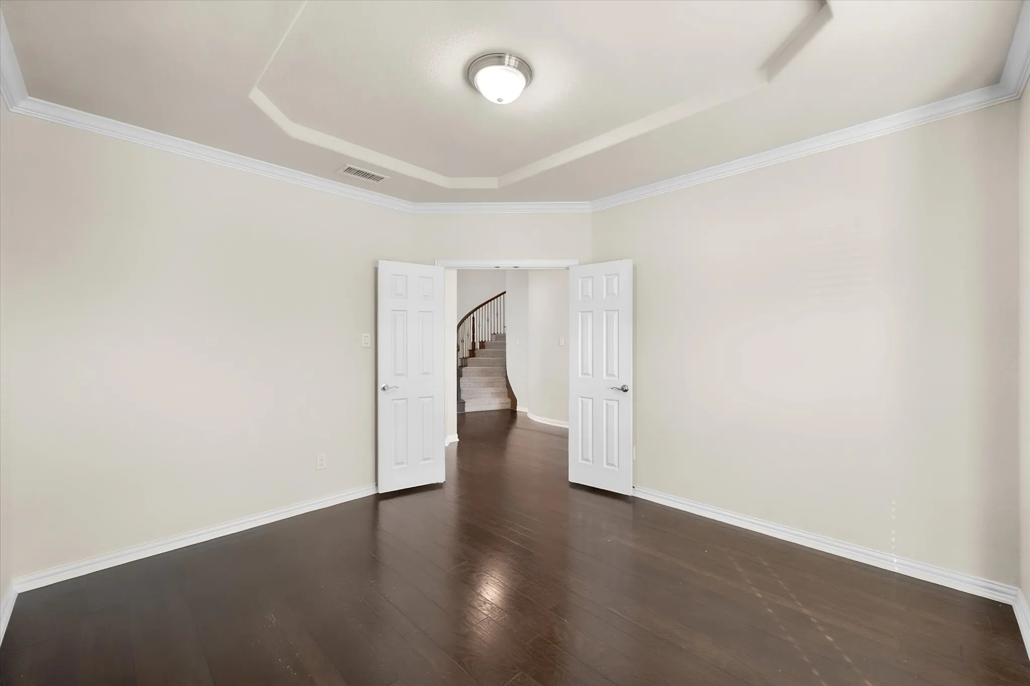 Recessed ceiling with crown molding, dark wood-finish flooring, and white paneled doors