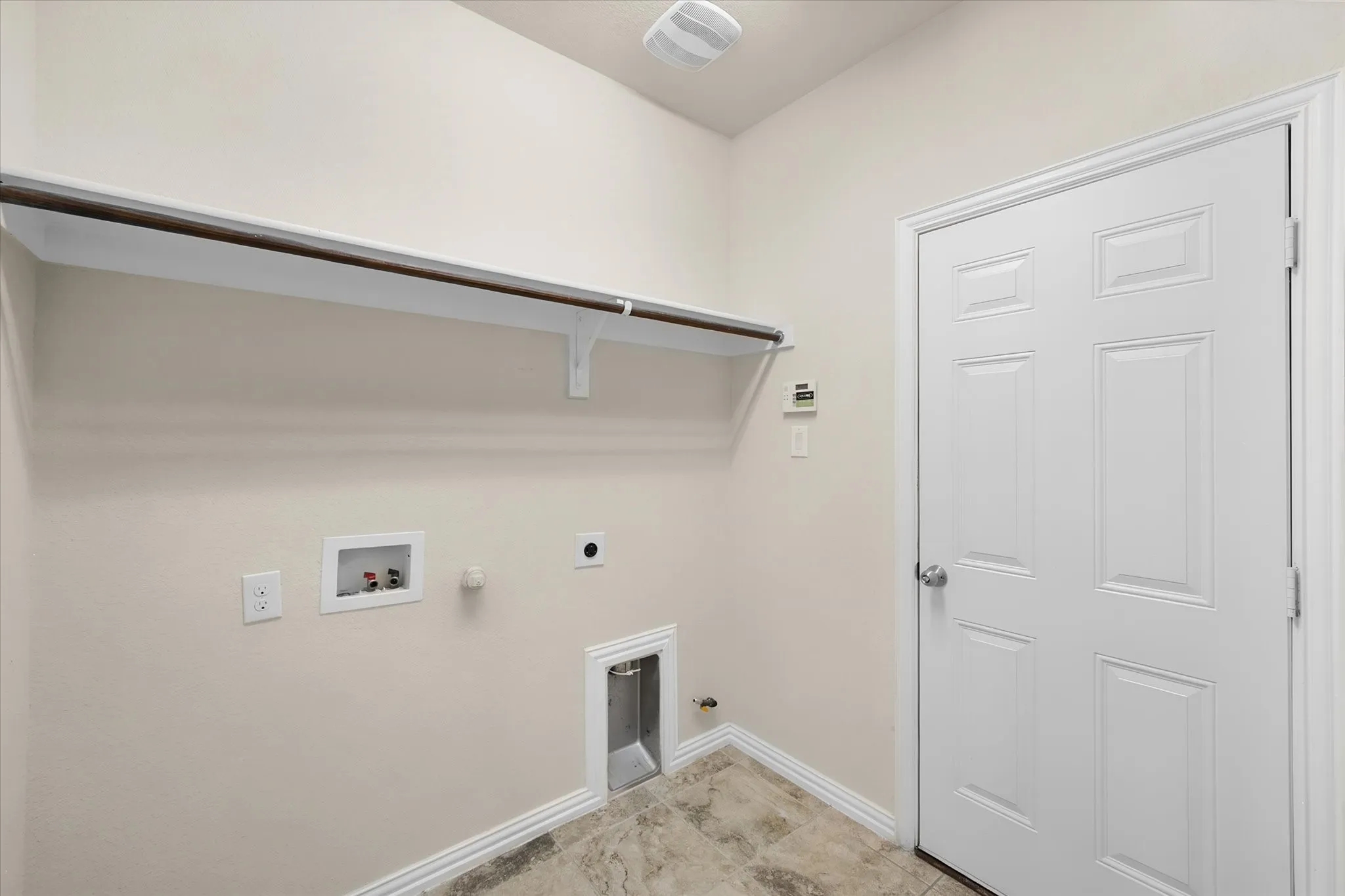 Utility area with tile flooring, built-in shelving, and a hanging rod