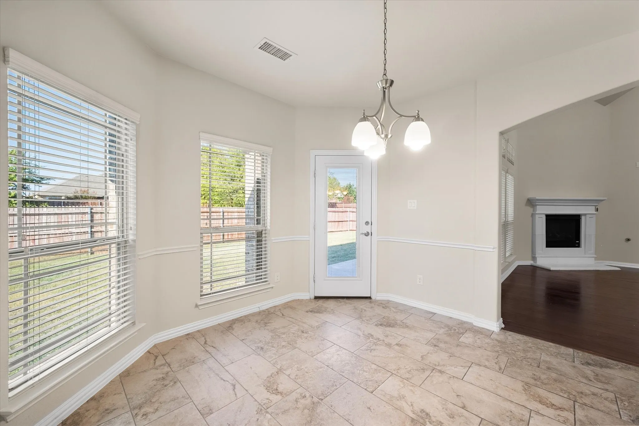 Tile flooring, bay windows, glass-paneled door, chandelier, and a decorative fireplace