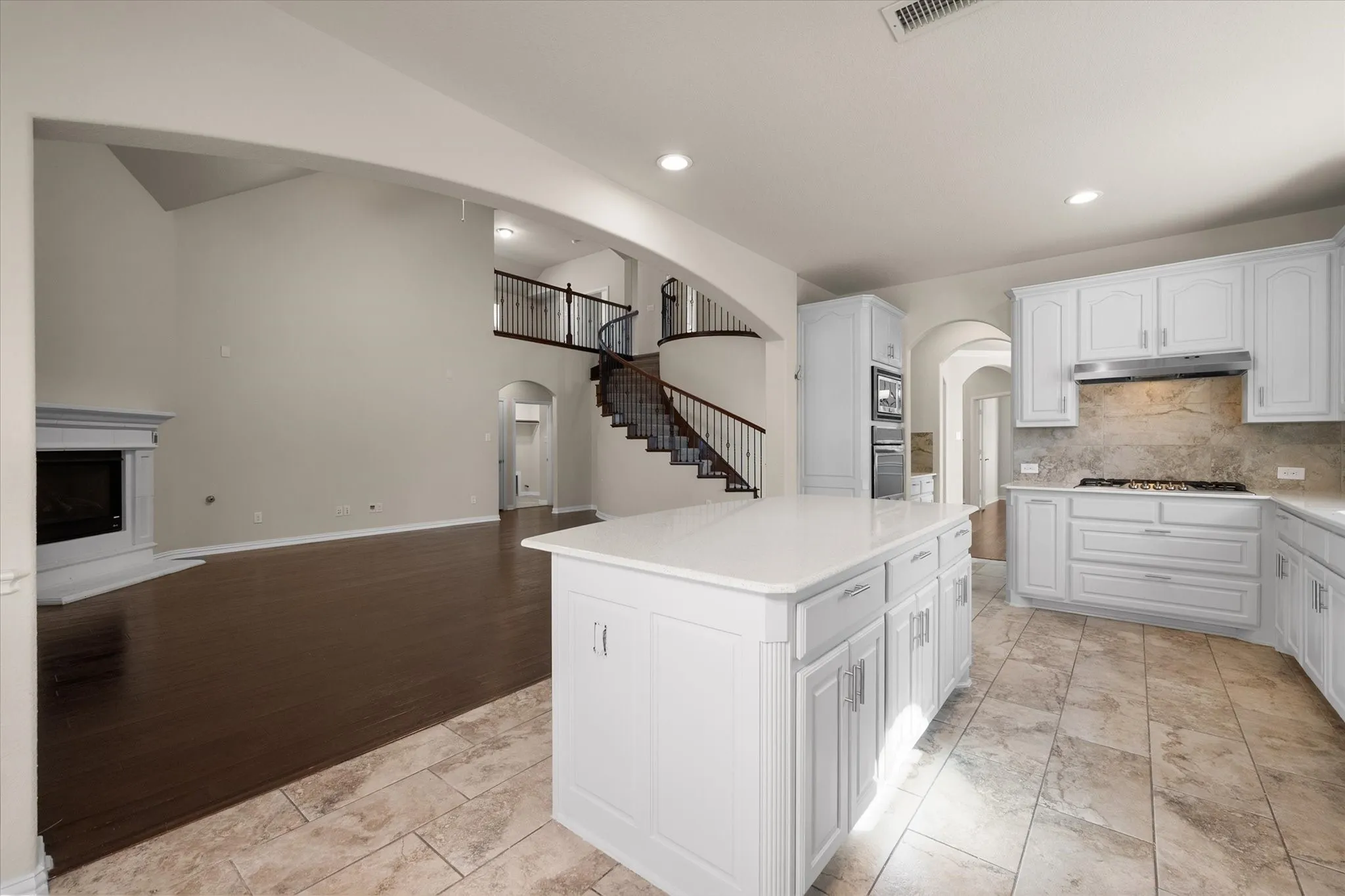 Gourmet kitchen featuring a central island, white cabinetry, integrated stainless steel appliances, and tile flooring