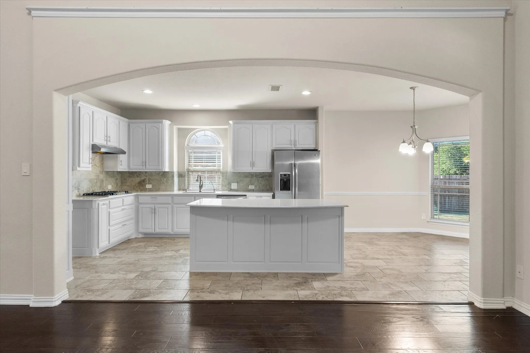 Spacious kitchen with white cabinetry, stainless steel appliances, a large center island, and tile flooring