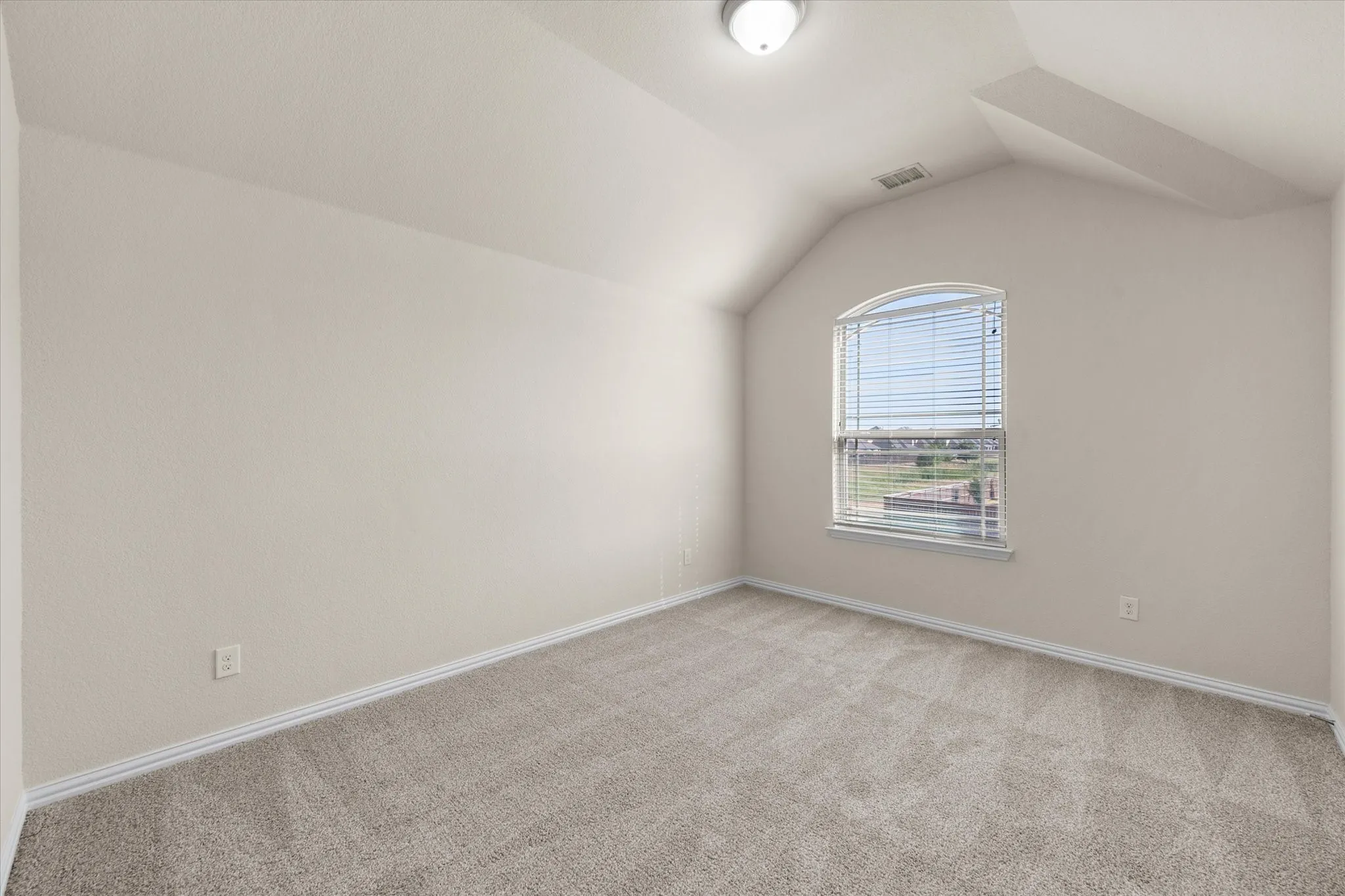 Arched window with blinds, sloped ceiling, light-toned carpeting, and a flush mount ceiling light