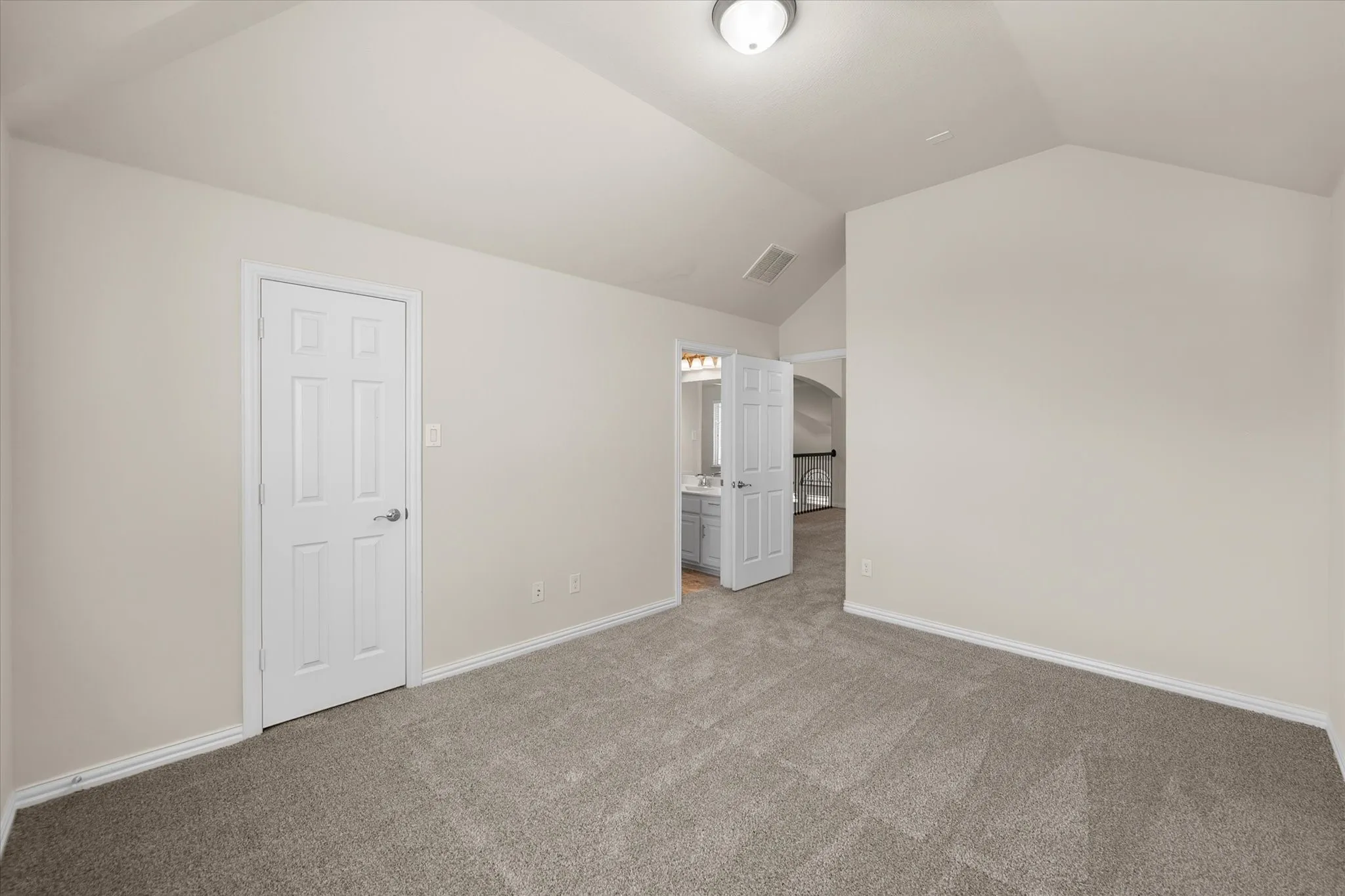 Vaulted ceiling, neutral wall paint, gray carpet flooring, white paneled door, flush mount ceiling light