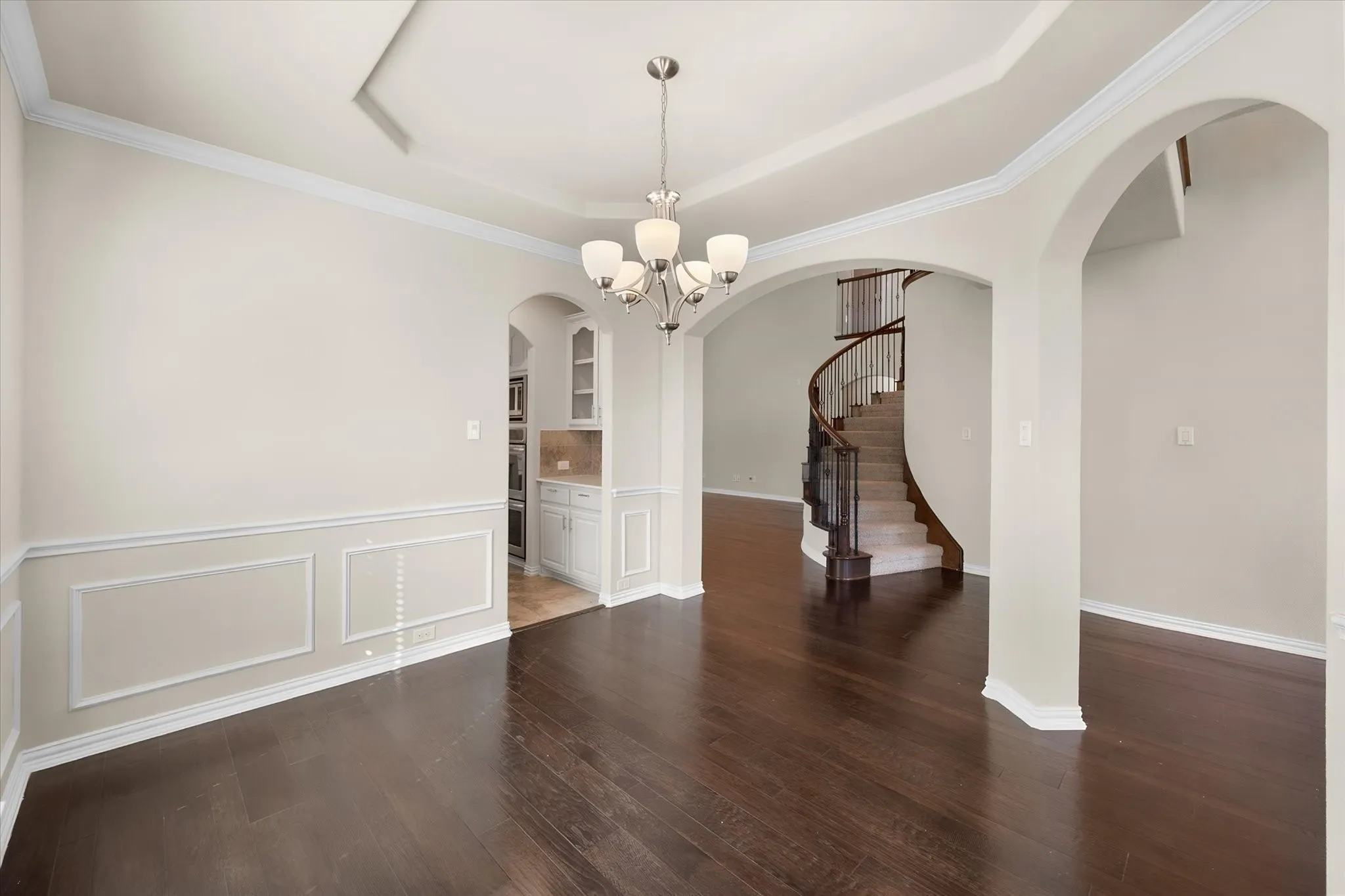 Hardwood-finish flooring, tray ceiling, wainscoting, arched doorways, and a built-in wet bar