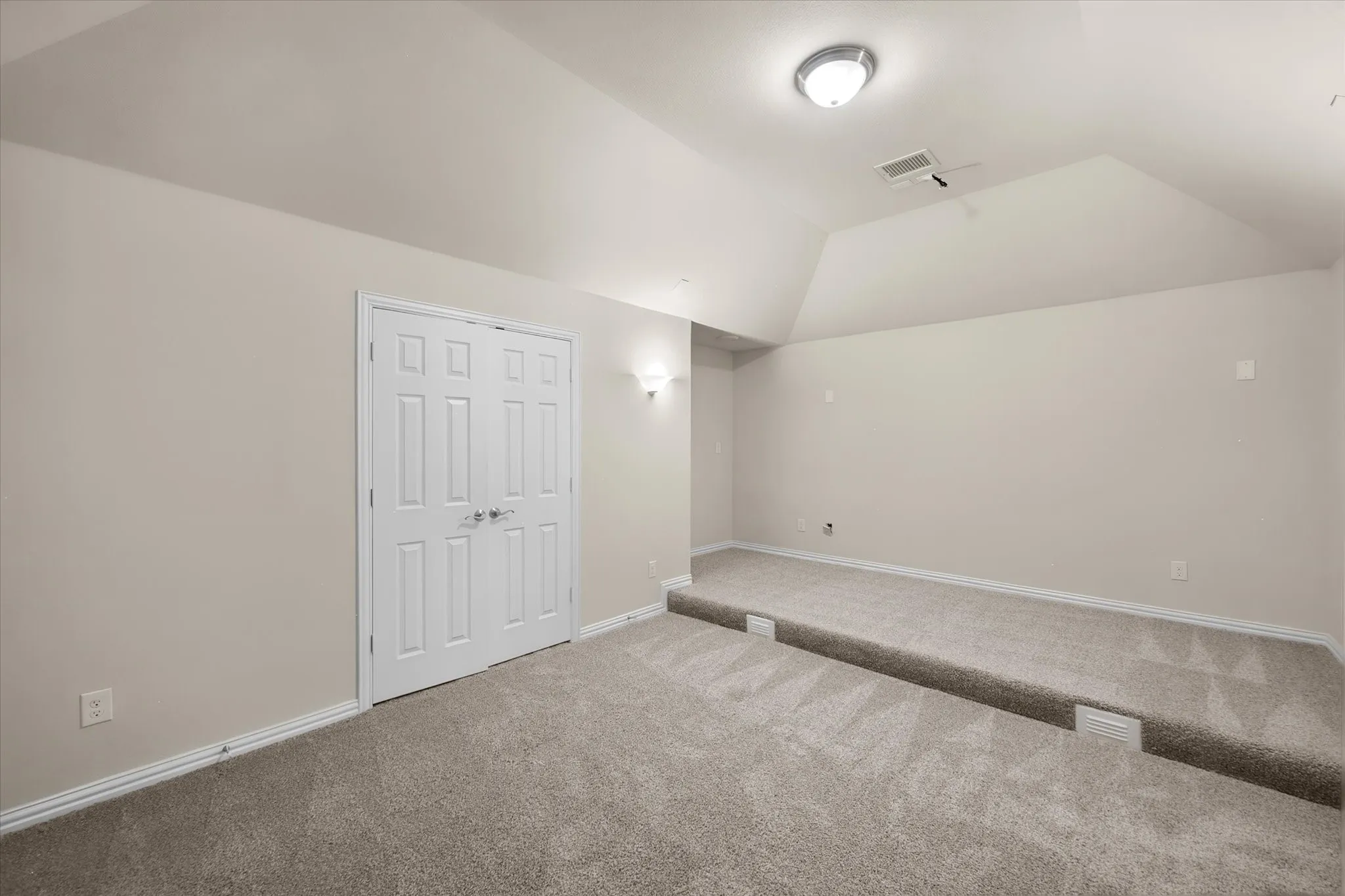 Carpeted room with a stepped floor, double panel doors, and neutral wall paint