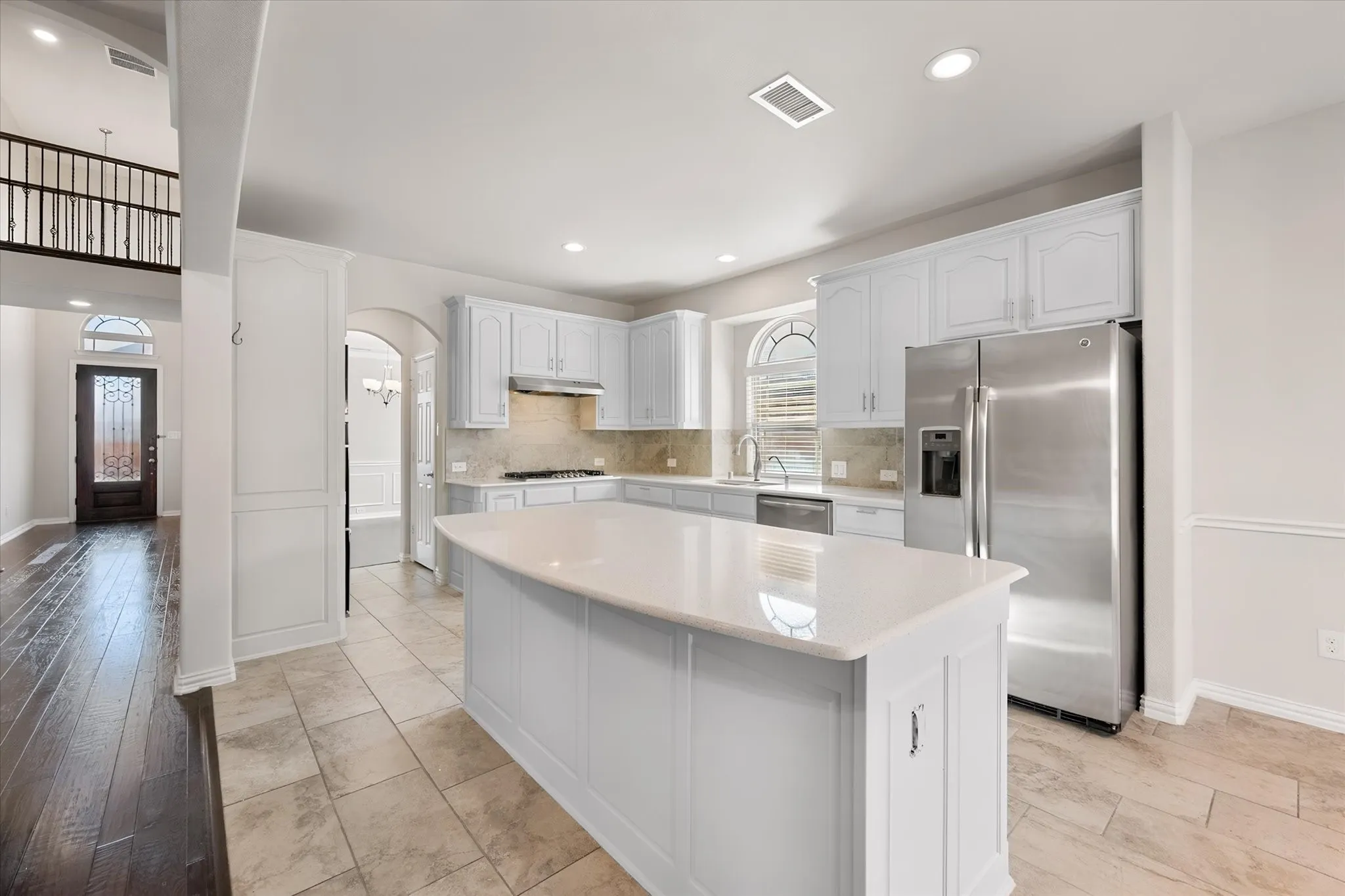 Kitchen featuring white cabinetry, stone countertops, stainless steel appliances, and a central island