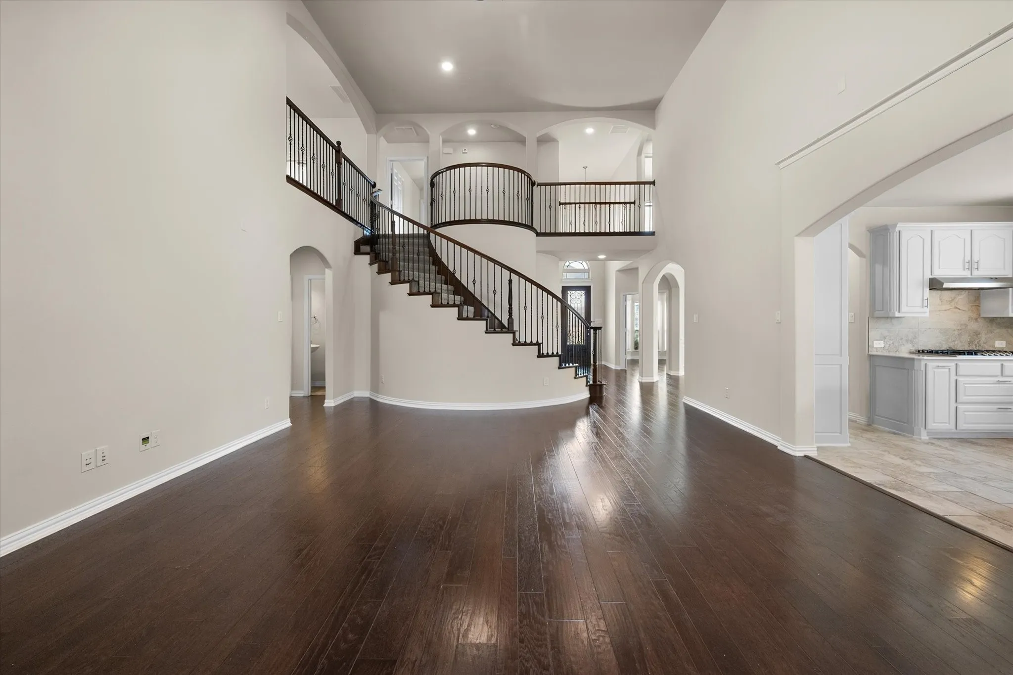 Expansive living area with wood-finish flooring, high ceilings, and recessed lighting