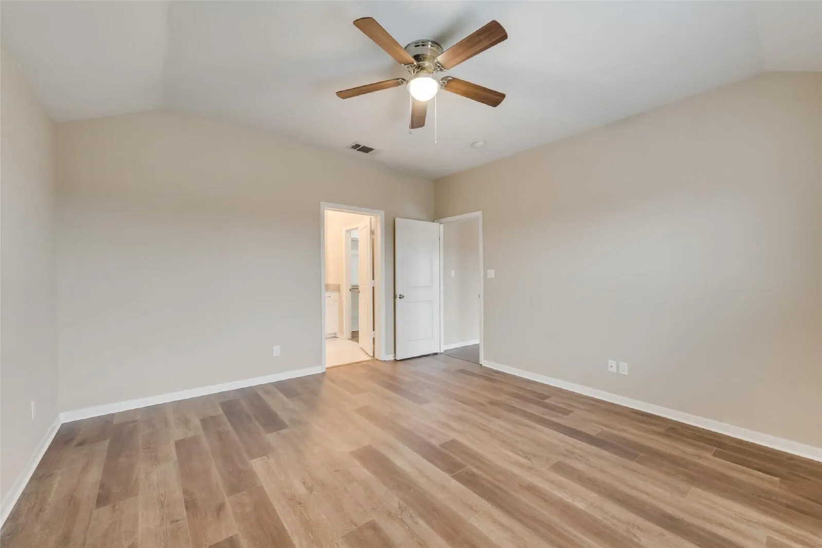Vaulted ceiling with a ceiling fan, wood-finish flooring, and light-colored walls