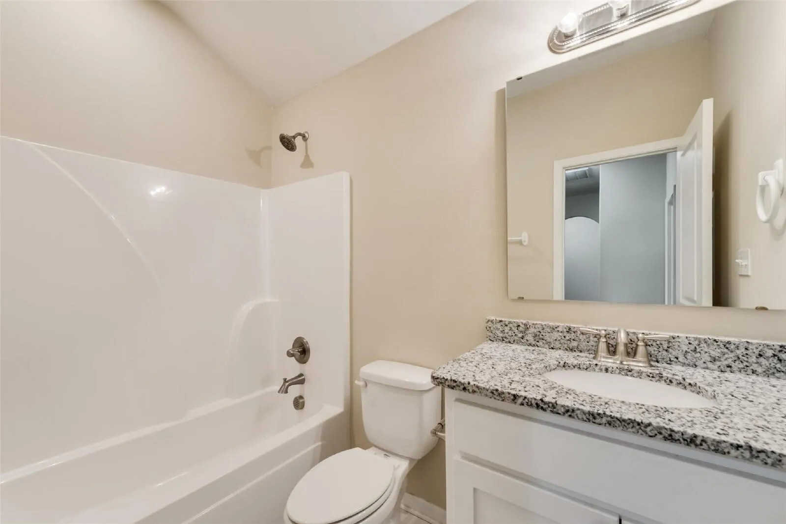 White vanity with a granite countertop, undermount sink, and brushed nickel faucet