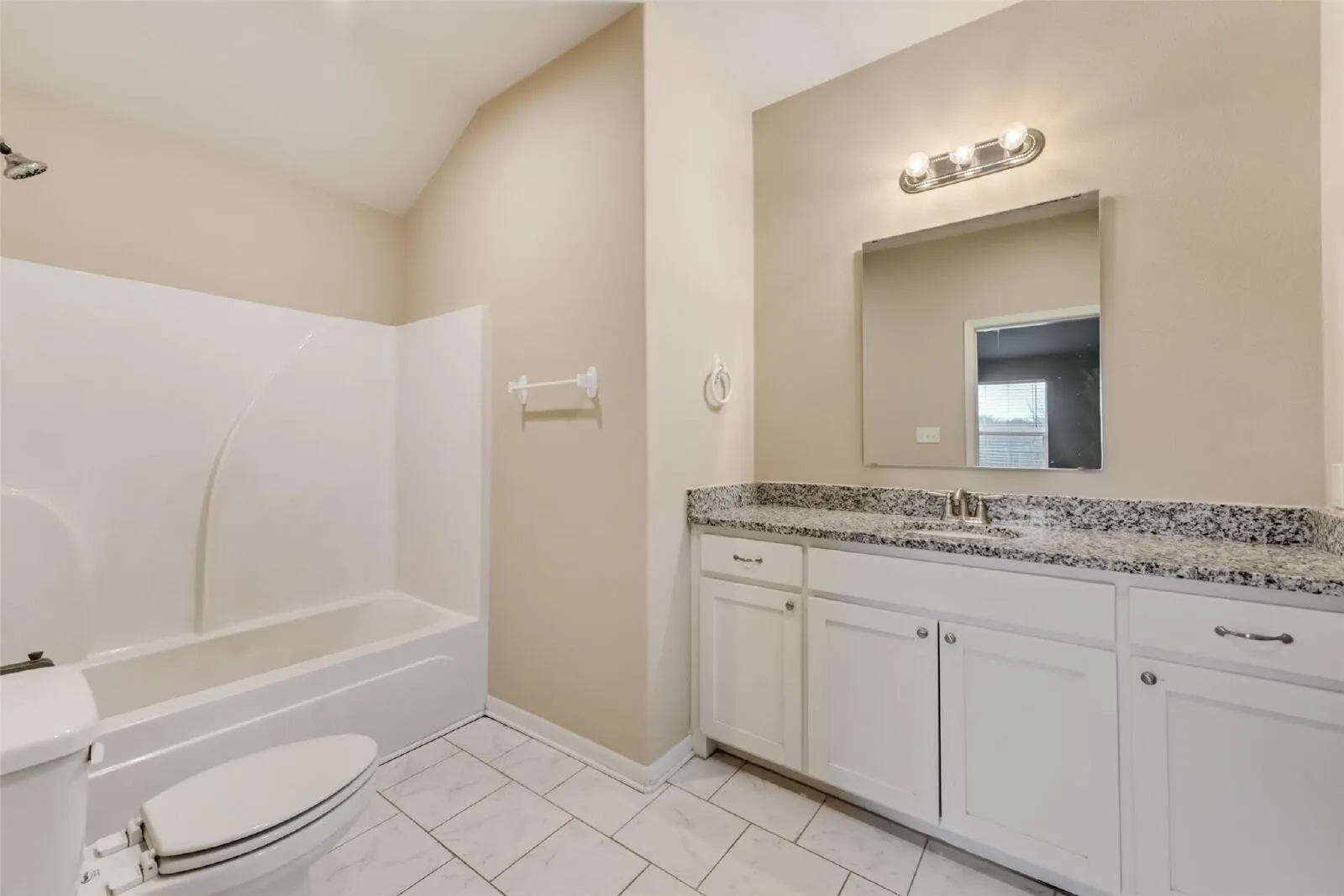 Shower-tub combination, ceramic tile flooring, double vanity with white cabinetry, integrated sink, and stone-finish countertop