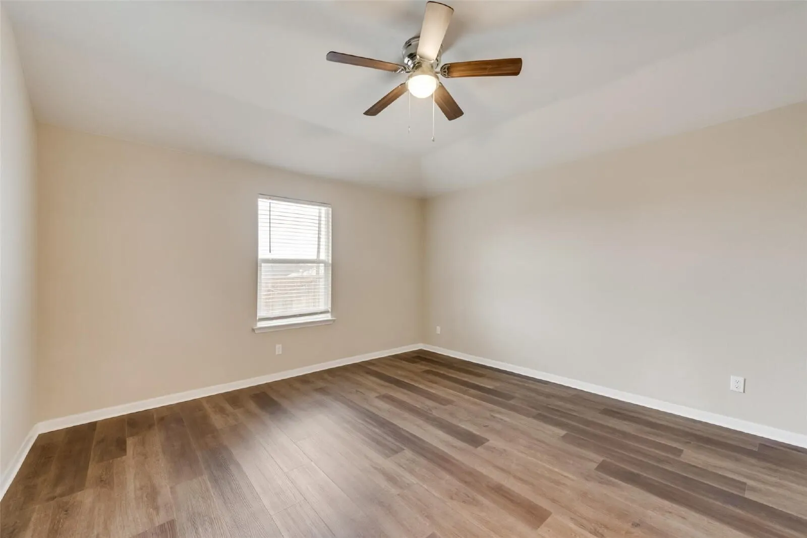 Recessed ceiling featuring a ceiling fan, wood-finish flooring, and a single window with blinds