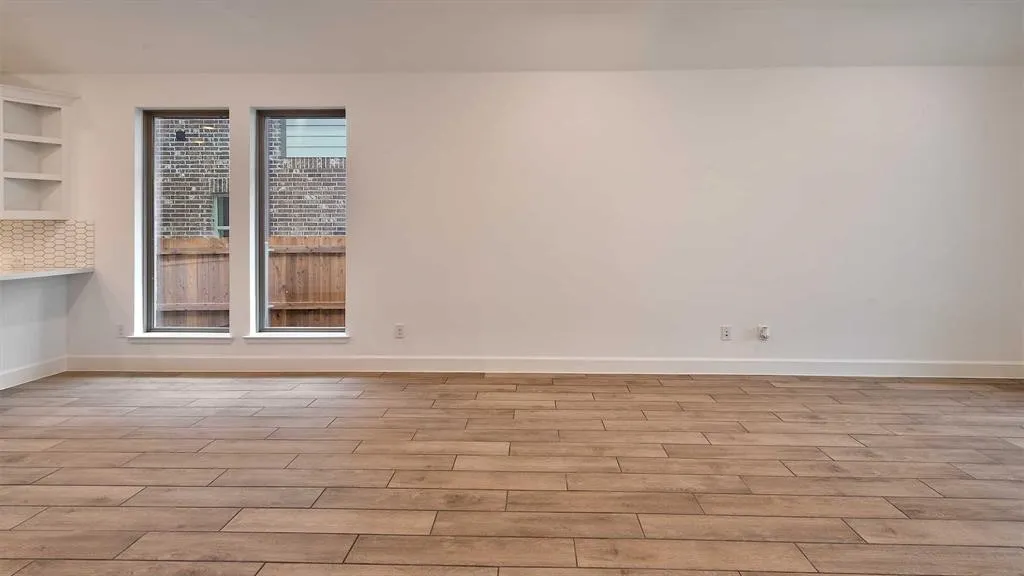 Wood-finish flooring, white walls, built-in shelving, two vertical windows, and a tiled backsplash