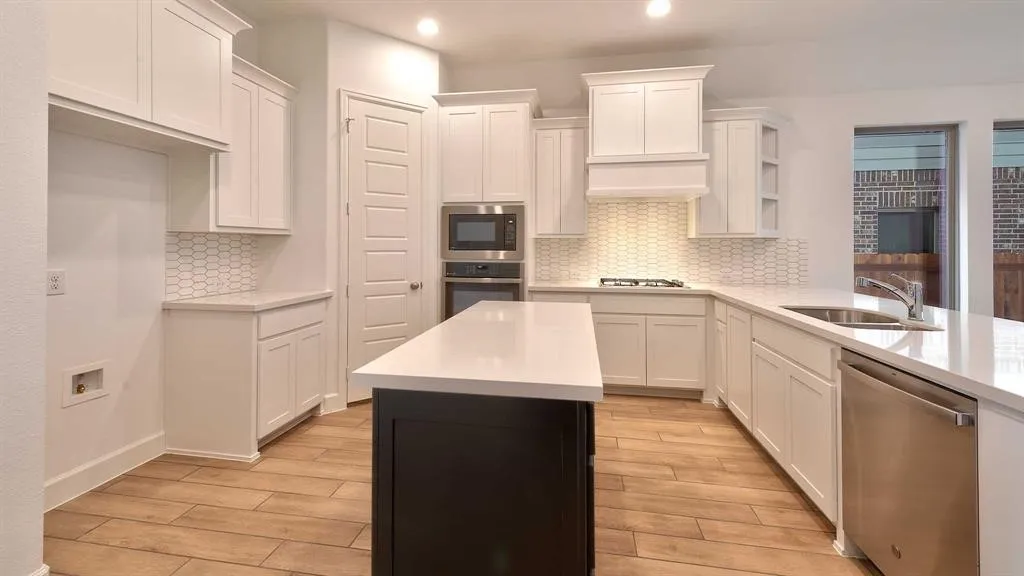 White shaker cabinetry with crown molding, wood-finish flooring, white solid surface countertops, stainless steel appliances, and a honeycomb tile backsplash