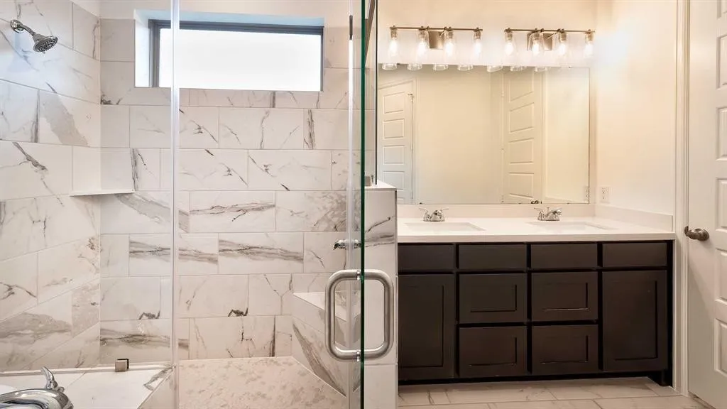 Glass-enclosed shower with white and grey tile surround and integrated shelving
