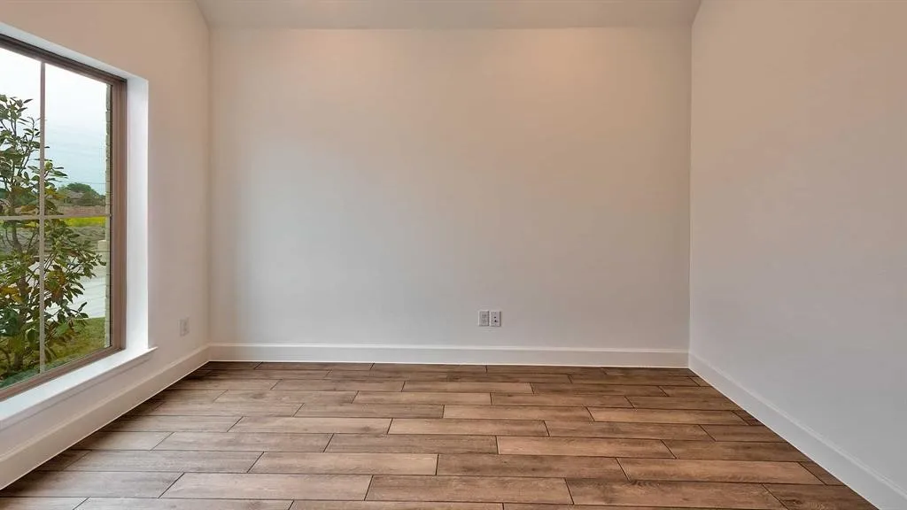 Wood-finish flooring with white baseboards and neutral wall paint