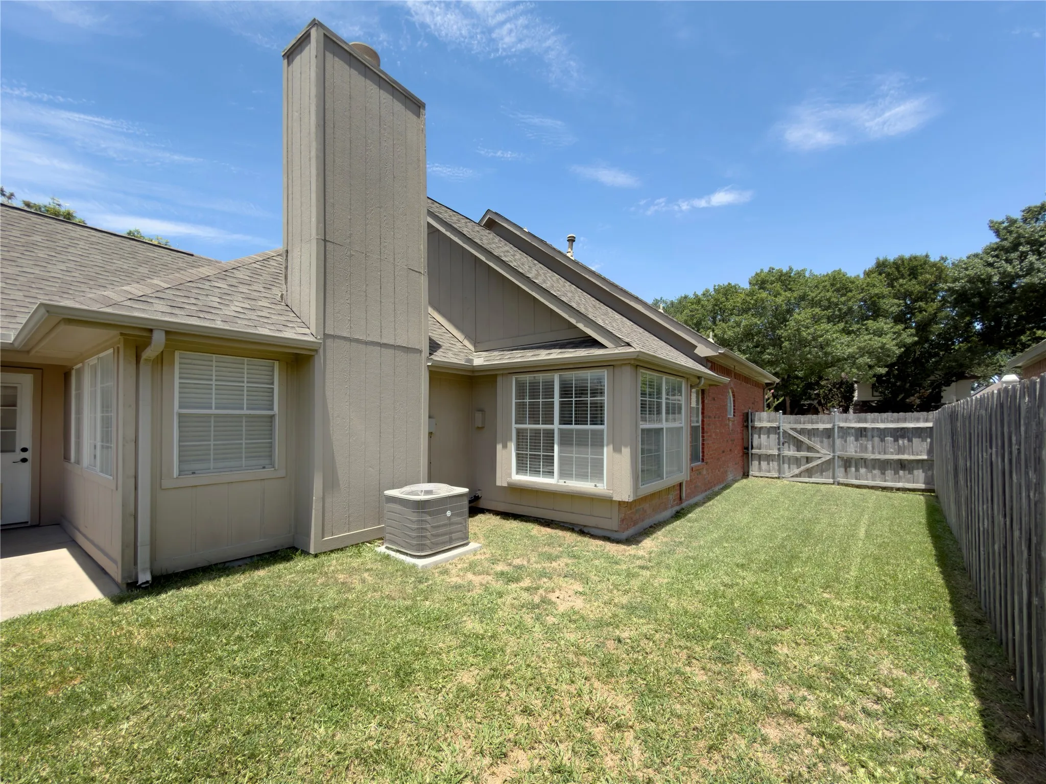 Private backyard featuring a wood fence, gate, and mature trees