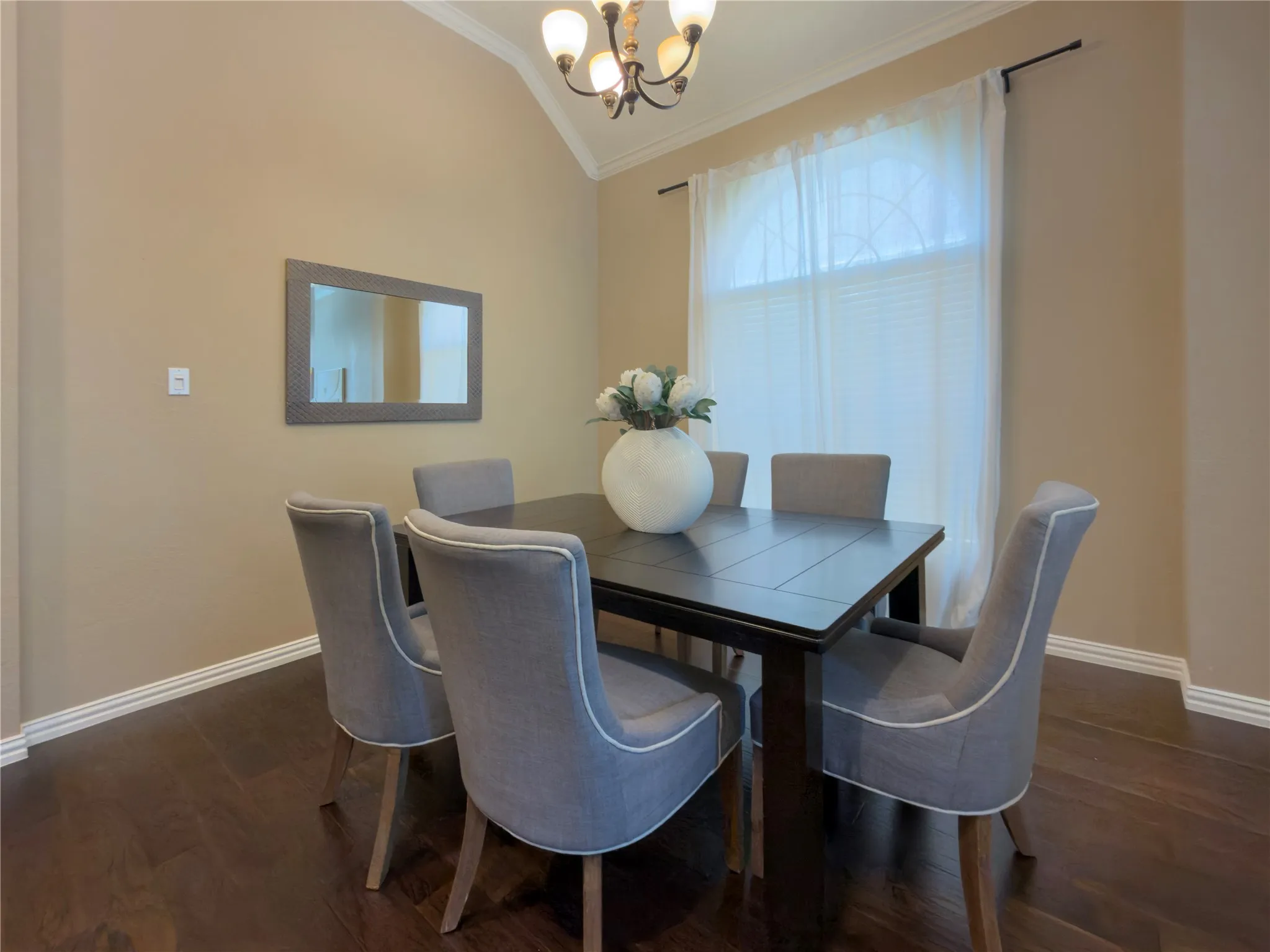 Vaulted ceiling with crown molding, wood-finish flooring, and a decorative chandelier