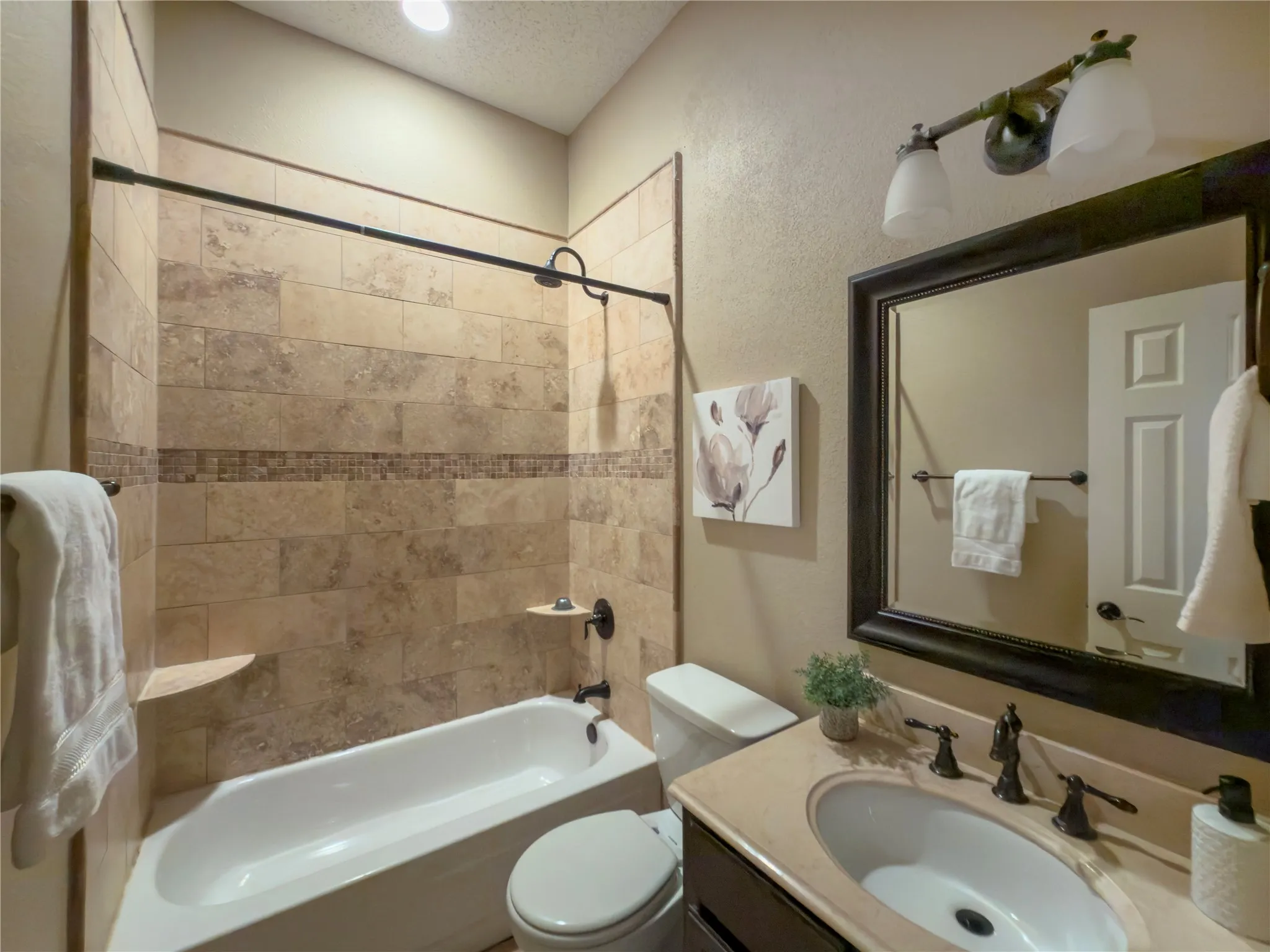 Soaking tub with a tiled surround, integrated shower, vanity with an undermount sink, and a framed mirror