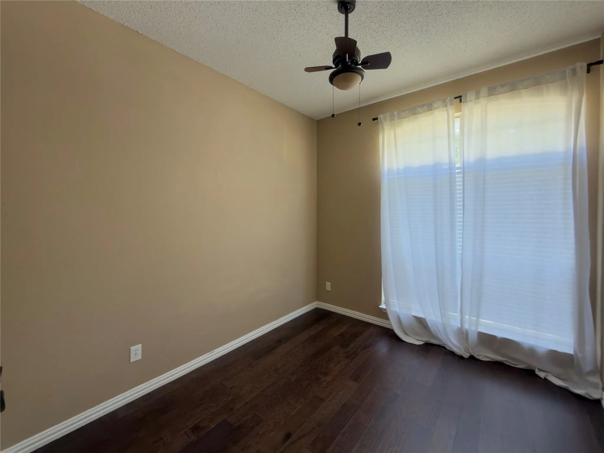 Wood-finish flooring with a ceiling fan light fixture and a window with blinds